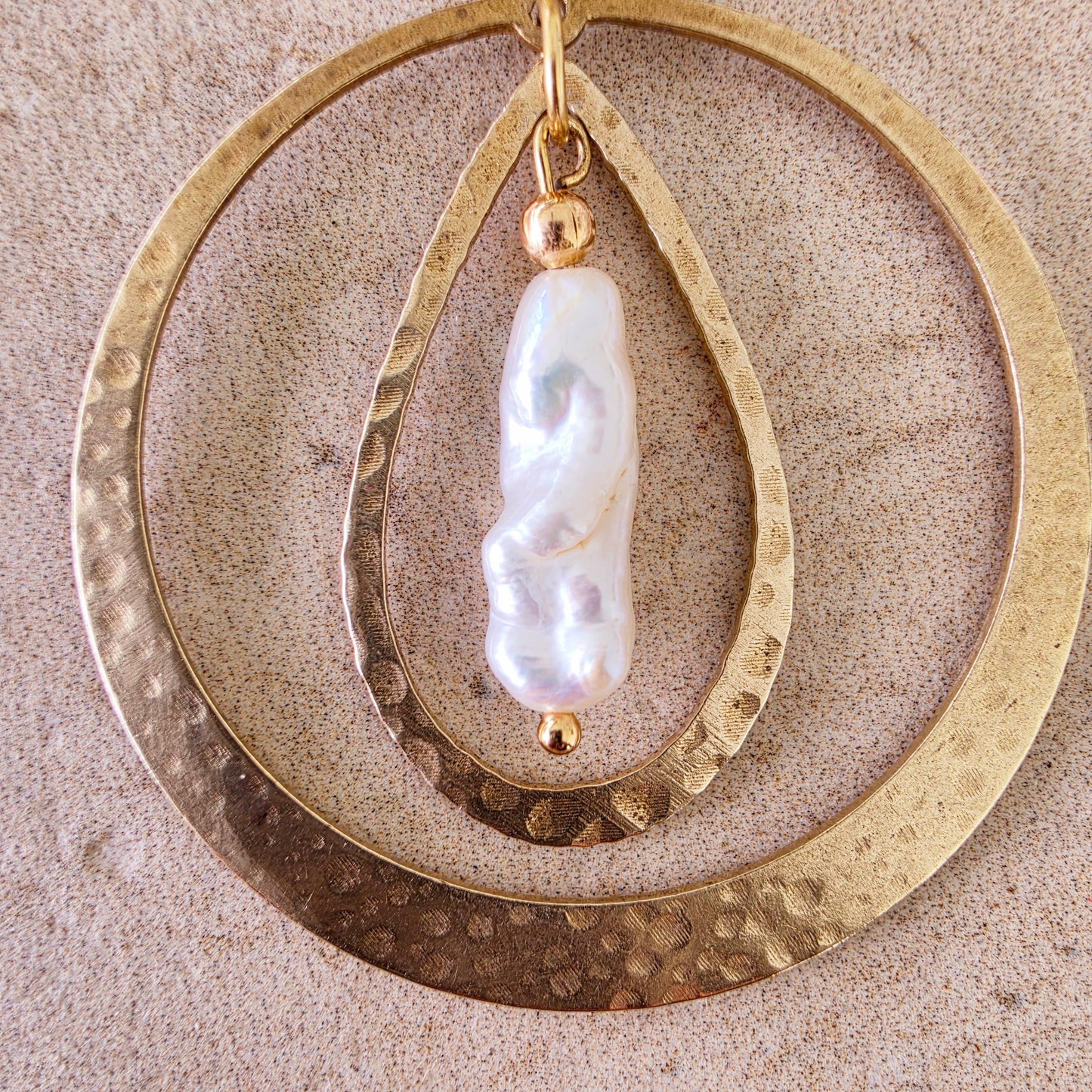 Close up view of the Kolekti earrings showing the hammered gold texture and feature pearl.