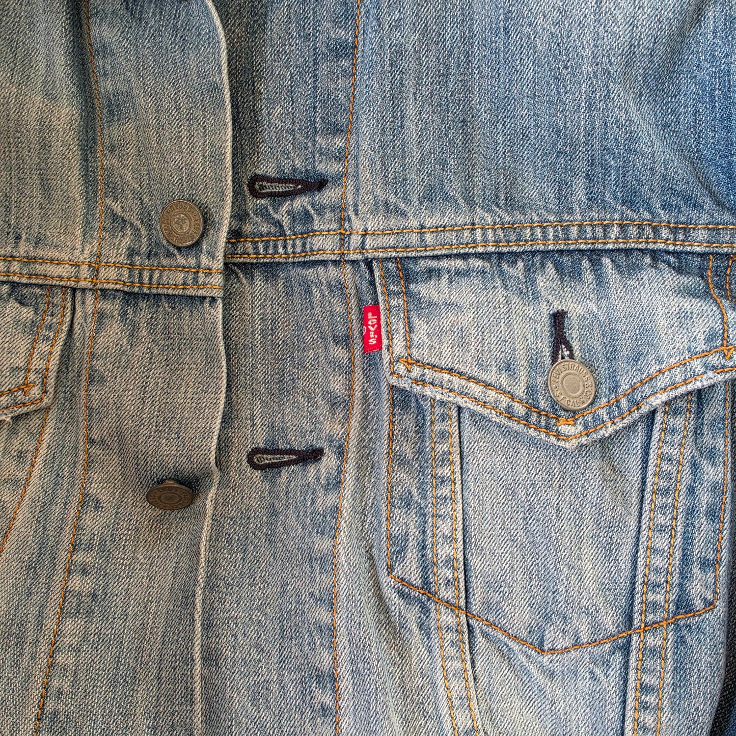 Close-up of Levi’s denim trucker jacket front with button closure and chest pocket detail