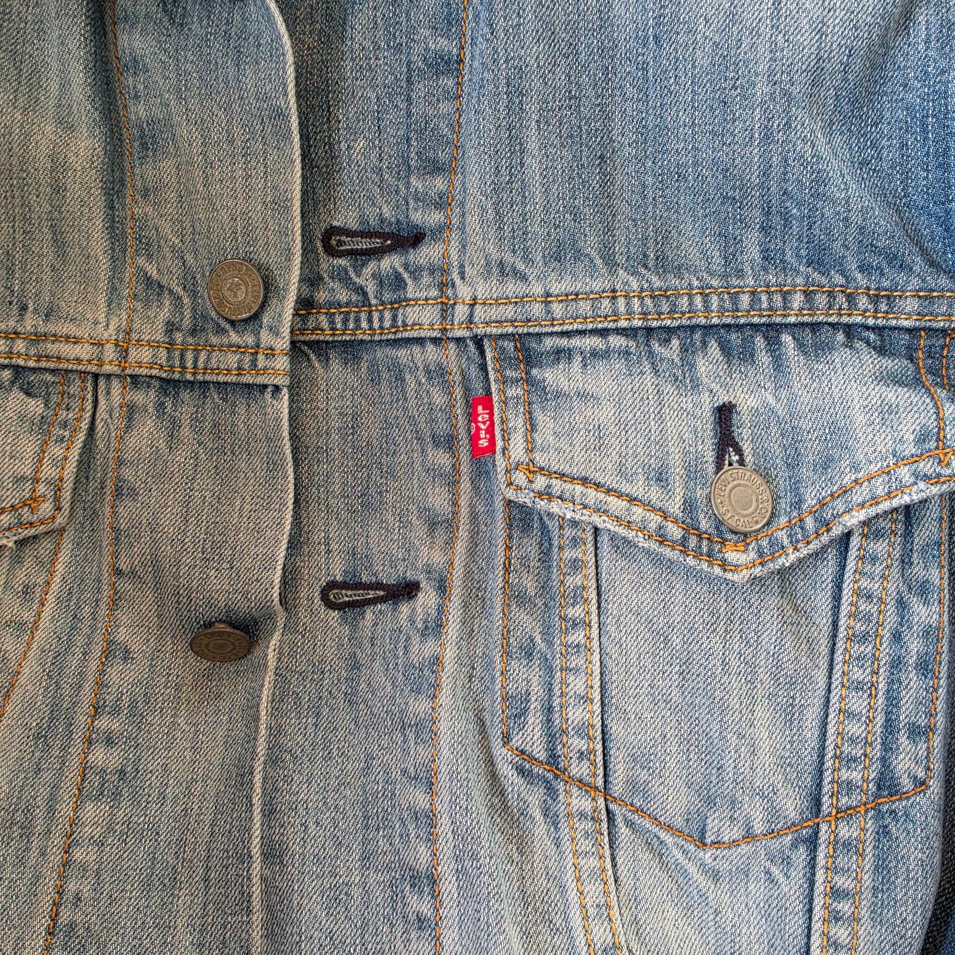 Close-up of Levi’s denim trucker jacket front with button closure and chest pocket detail