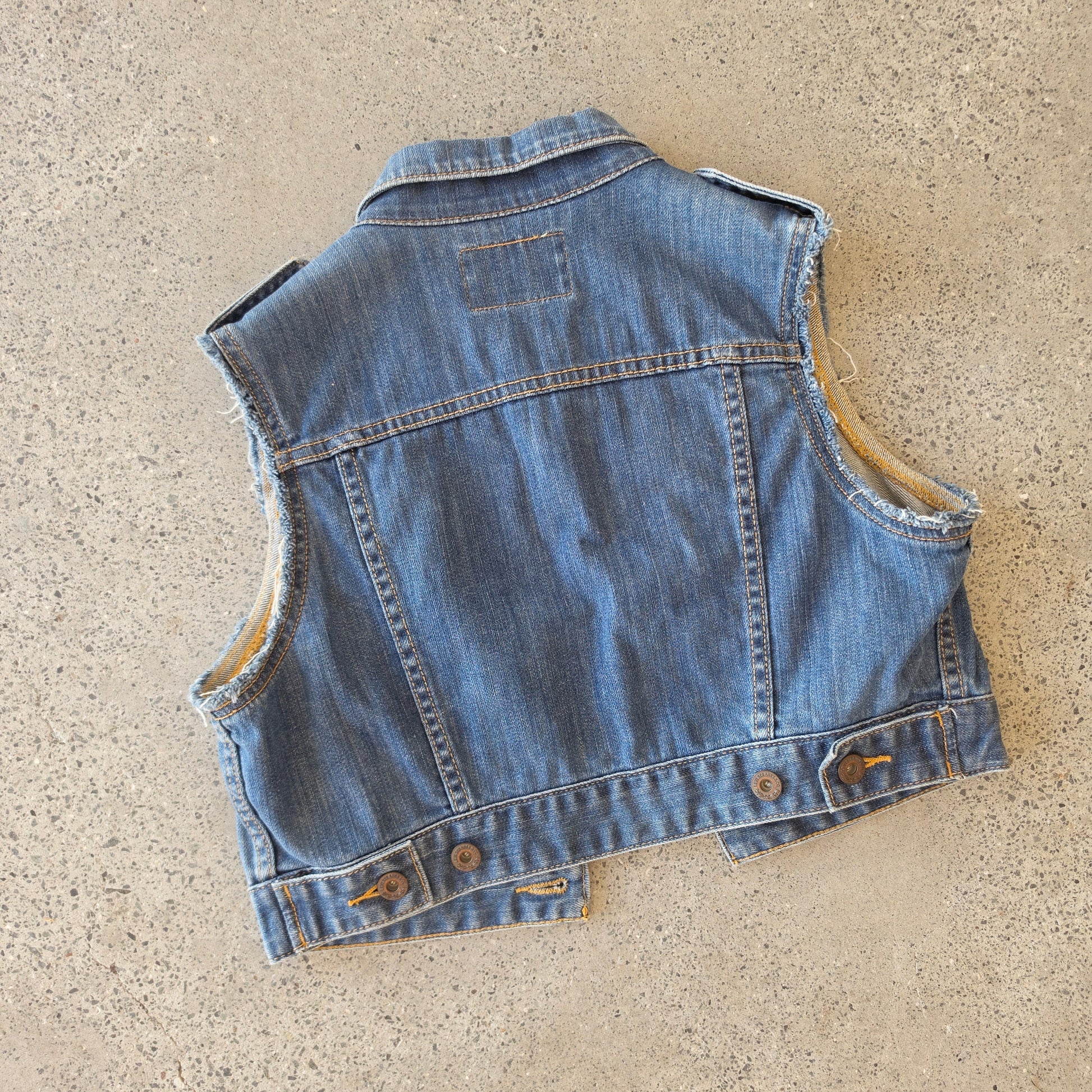 Flat lay of the back of the Levus denim vest showing the waist button details