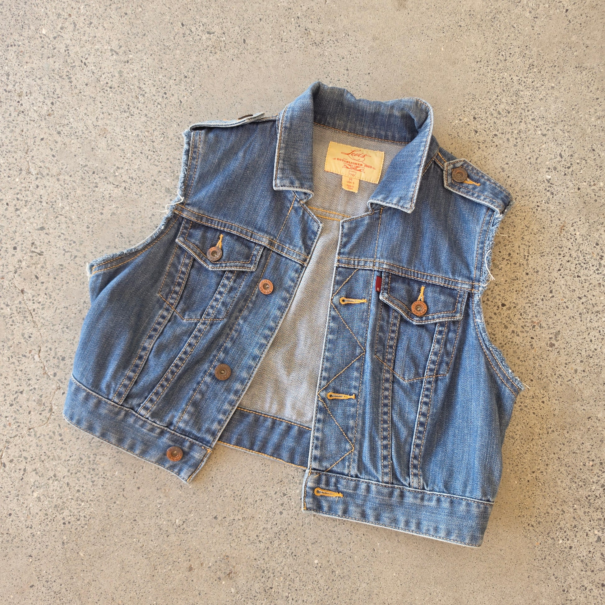 Flat lay of the Levis denim vest, showing the button front and cropped style.