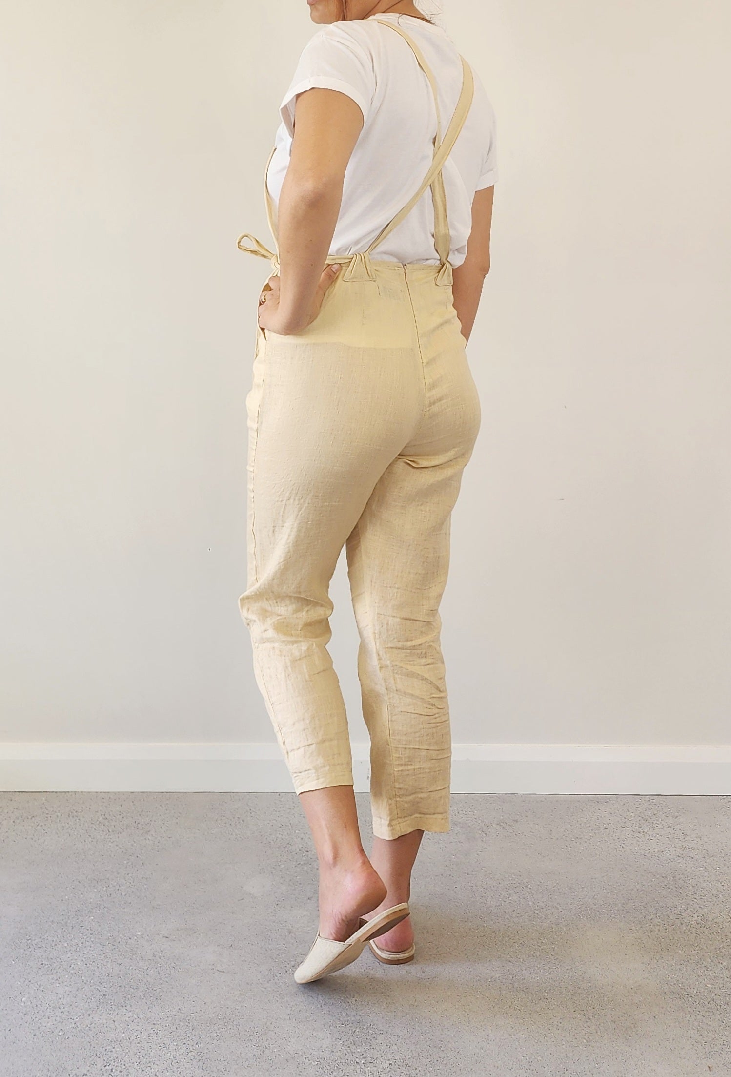 Back view of Lilya oatmeal linen overalls, highlighting adjustable straps and straight-leg cut.