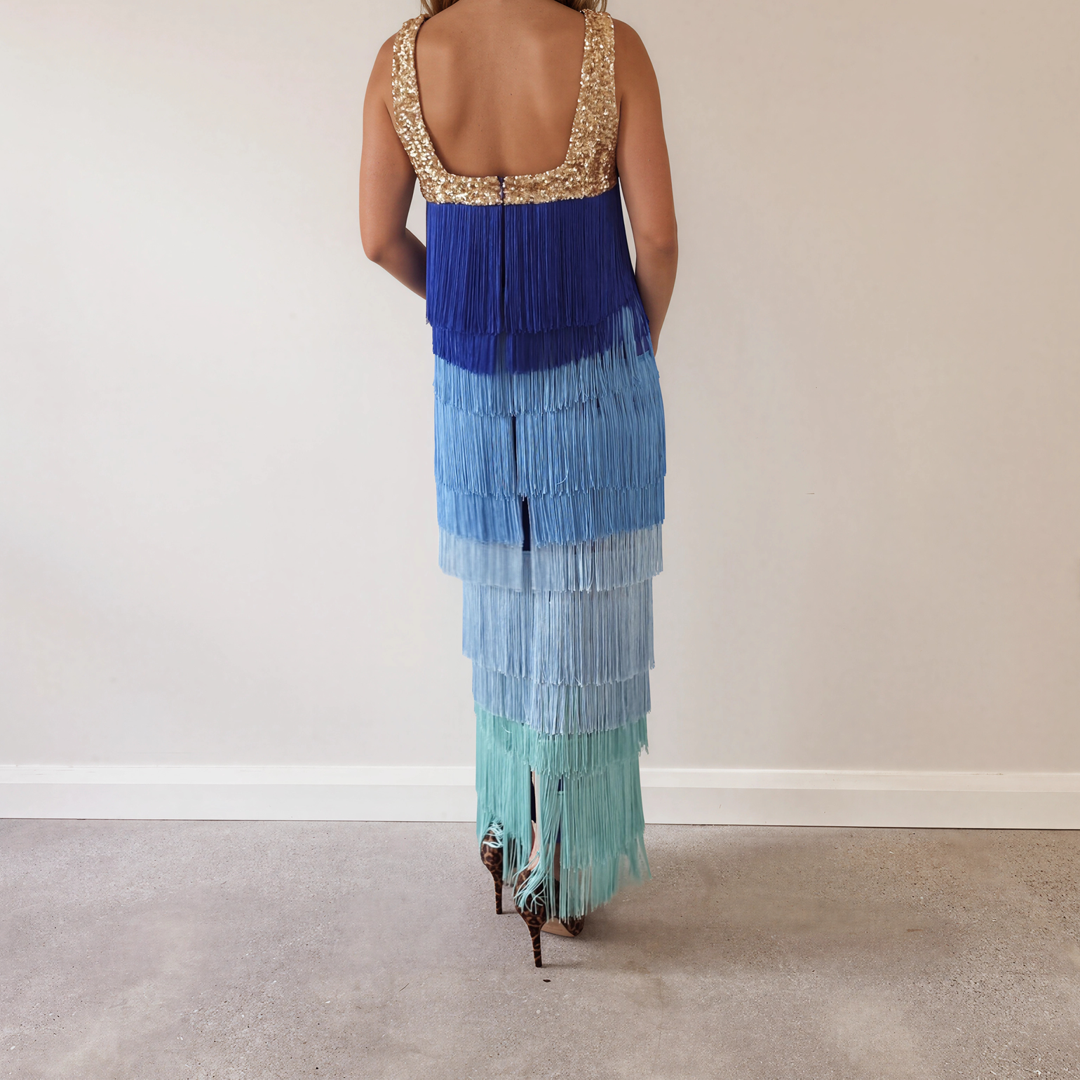 Image showing the back of a model wearing the Love Bonfire The Label Jewel Skies fringe midi dress with gold sequin neckline and blue ombré tassels.
