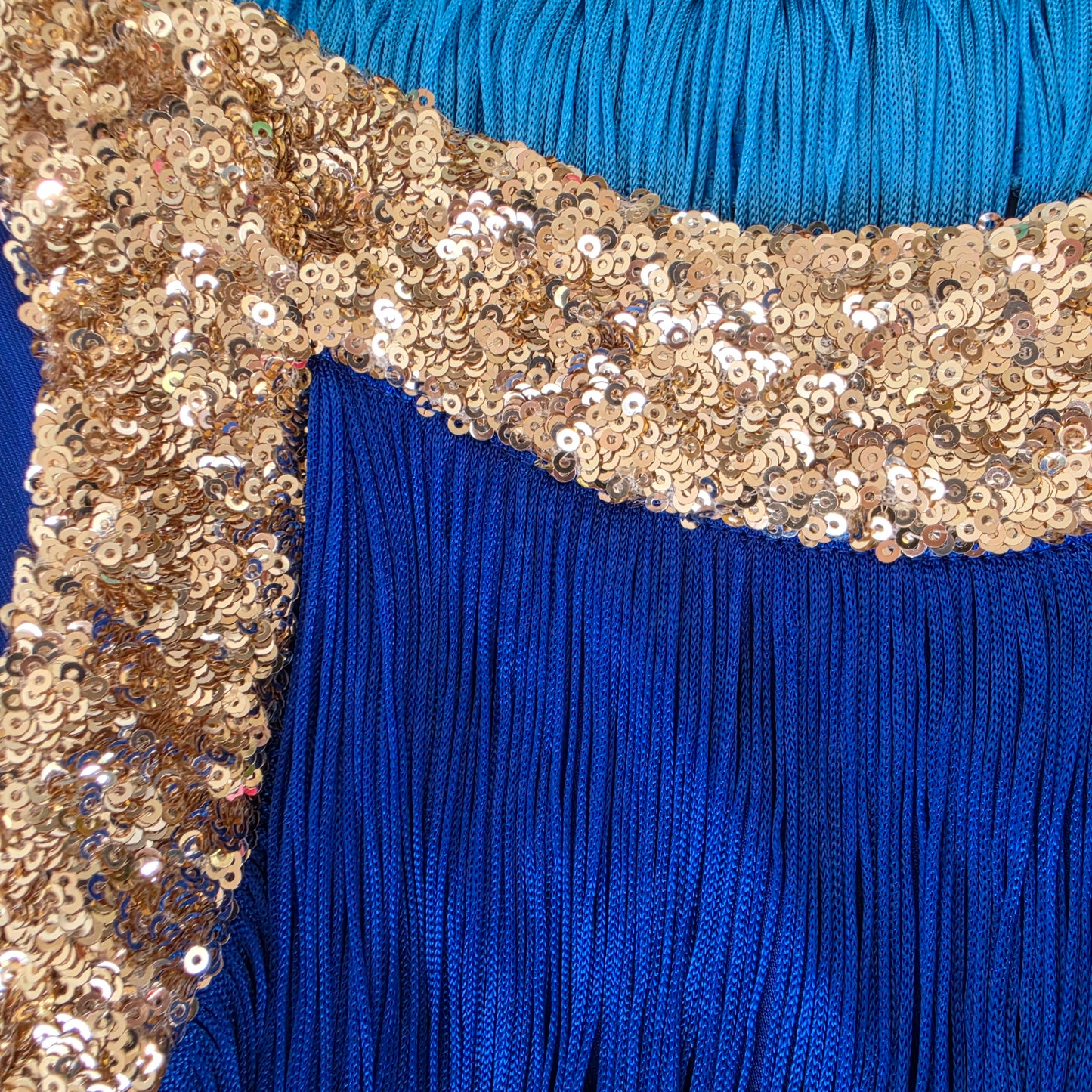 Close-up of the Love Bonfire Jewel Skies blue fringed dress showing the  wide gold sequined trim neckline