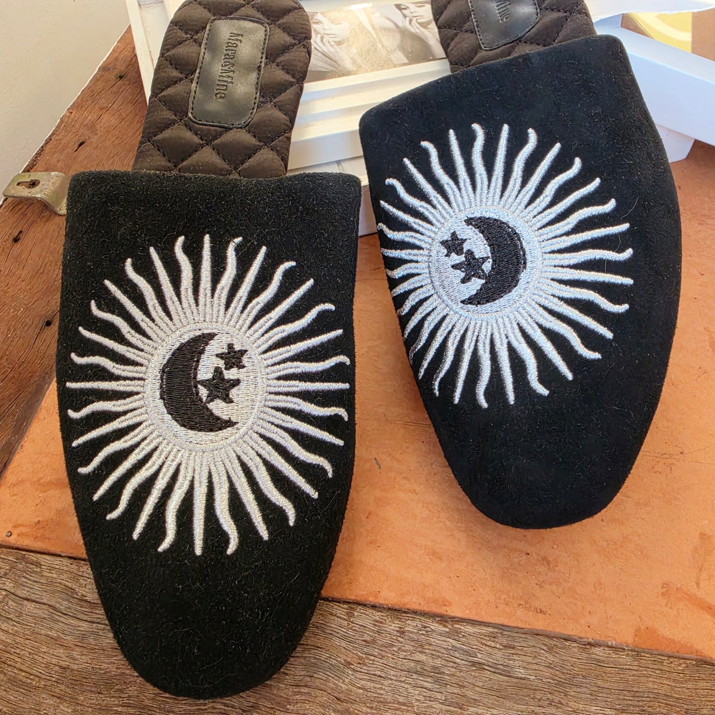 Top view Mara and Mine Estrella slides showing the silver and black embroidered sun moon design.