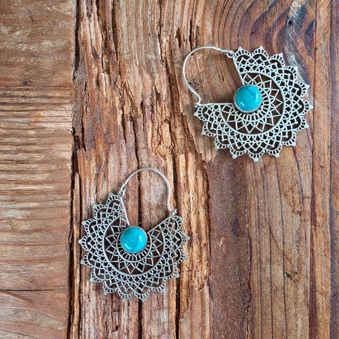 Pair of bohemian filigree earrings on textured wood surface