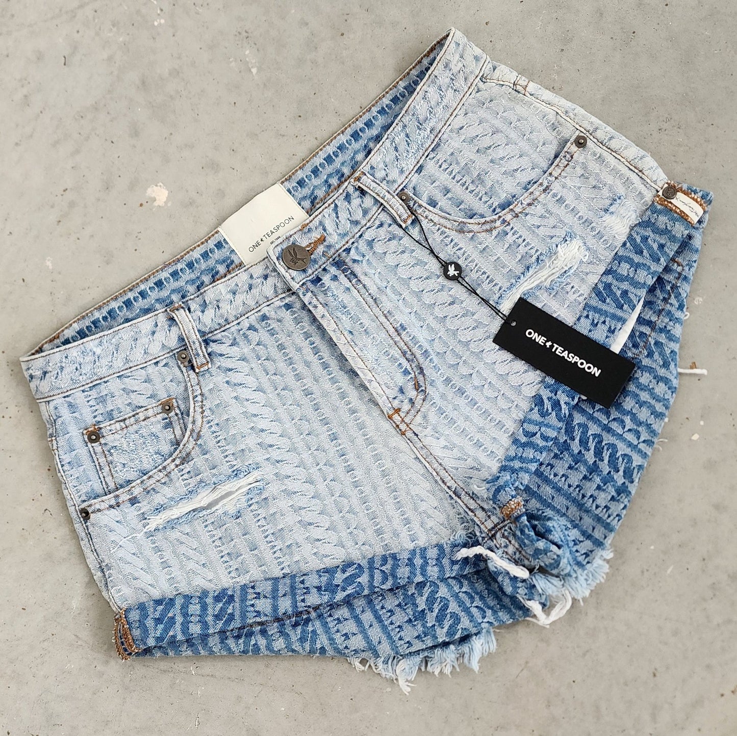 Image of the One Teaspoon bandit shorts, showing the exclusive print "on repeat", the One Teaspoon swing tag and factory distress