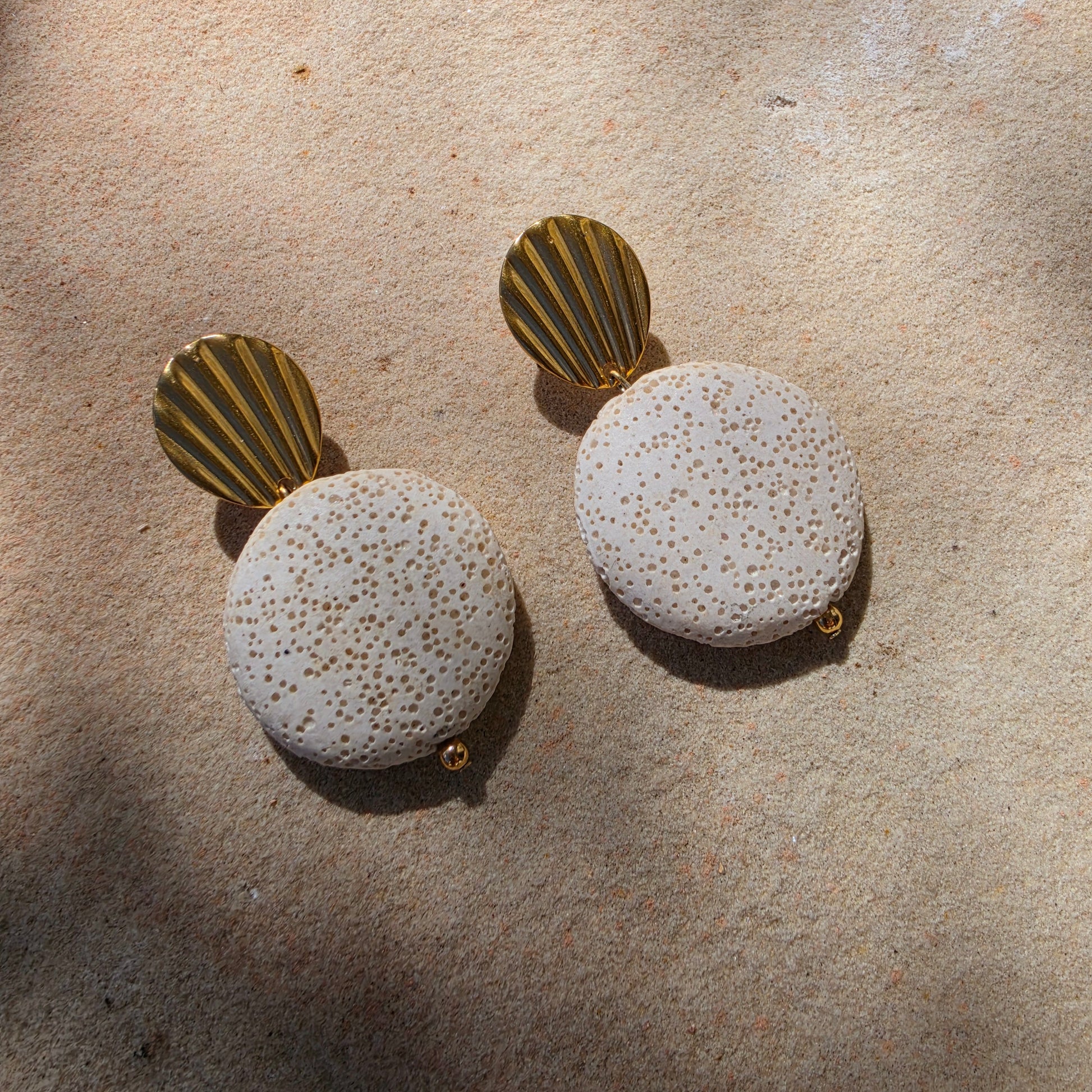 Front view of the Lumen Crema earring, part of the Relic collection, showing the shell like gold plated component and textured surface