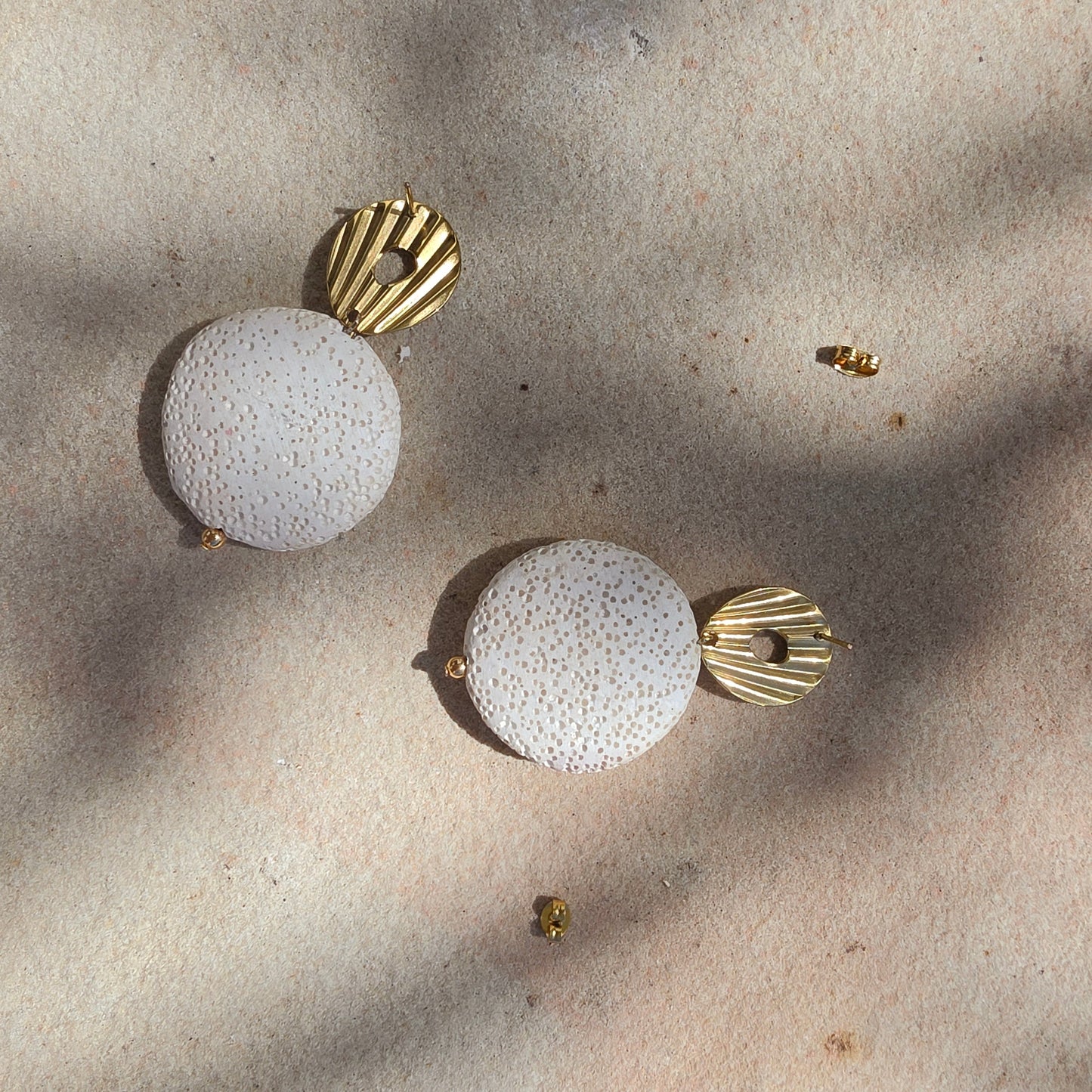Close-up view of Relic Lumen earrings in crema, showing the texture of the earrings and the stud closure