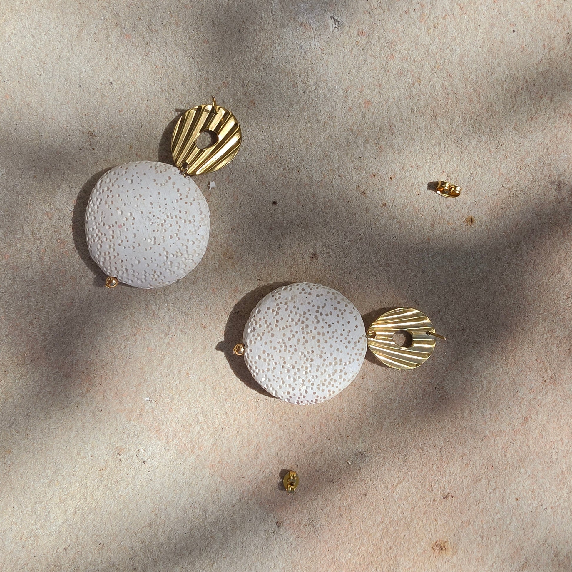 Close-up view of Relic Lumen earrings in crema, showing the texture of the earrings and the stud closure