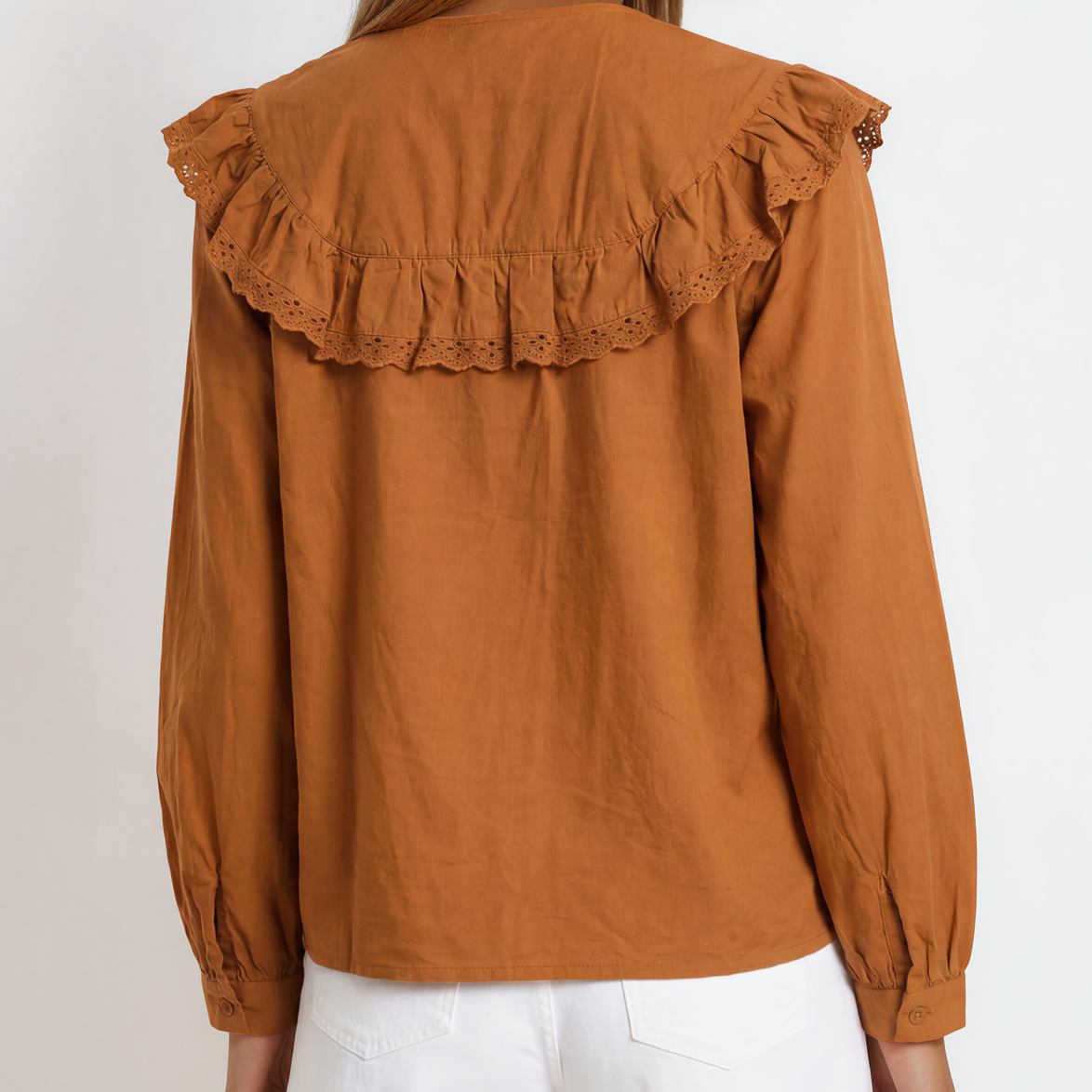 Back view of woman wearing a brown blouse with ruffled shoulders on a white background