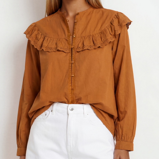 Image showing a woman wearing the rust coloured  long-sleeve blouse with a large ruffled lace collar and button front.