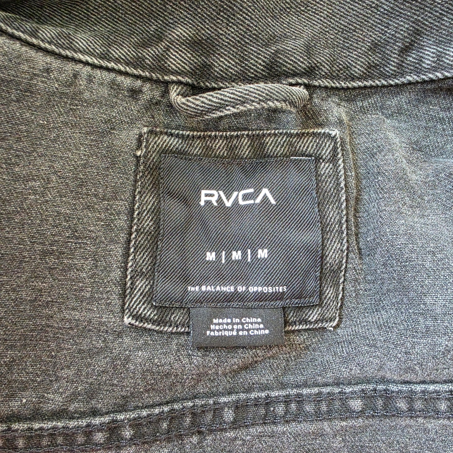 RVCA label inside black denim jacket, size medium, worn-in fabric detail