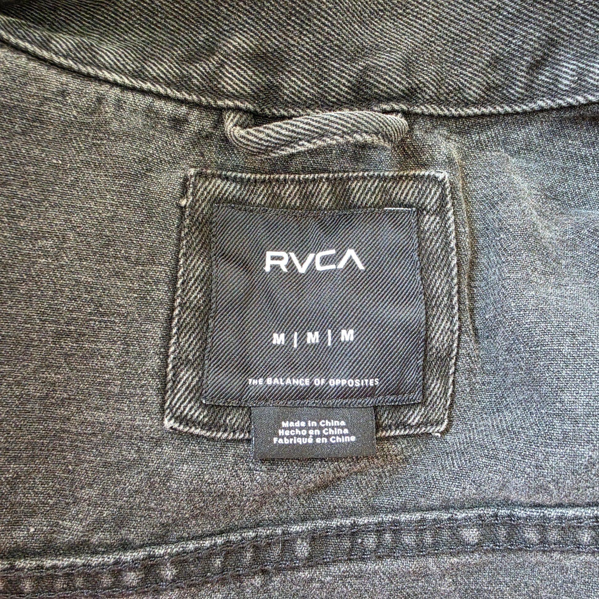 RVCA label inside black denim jacket, size medium, worn-in fabric detail