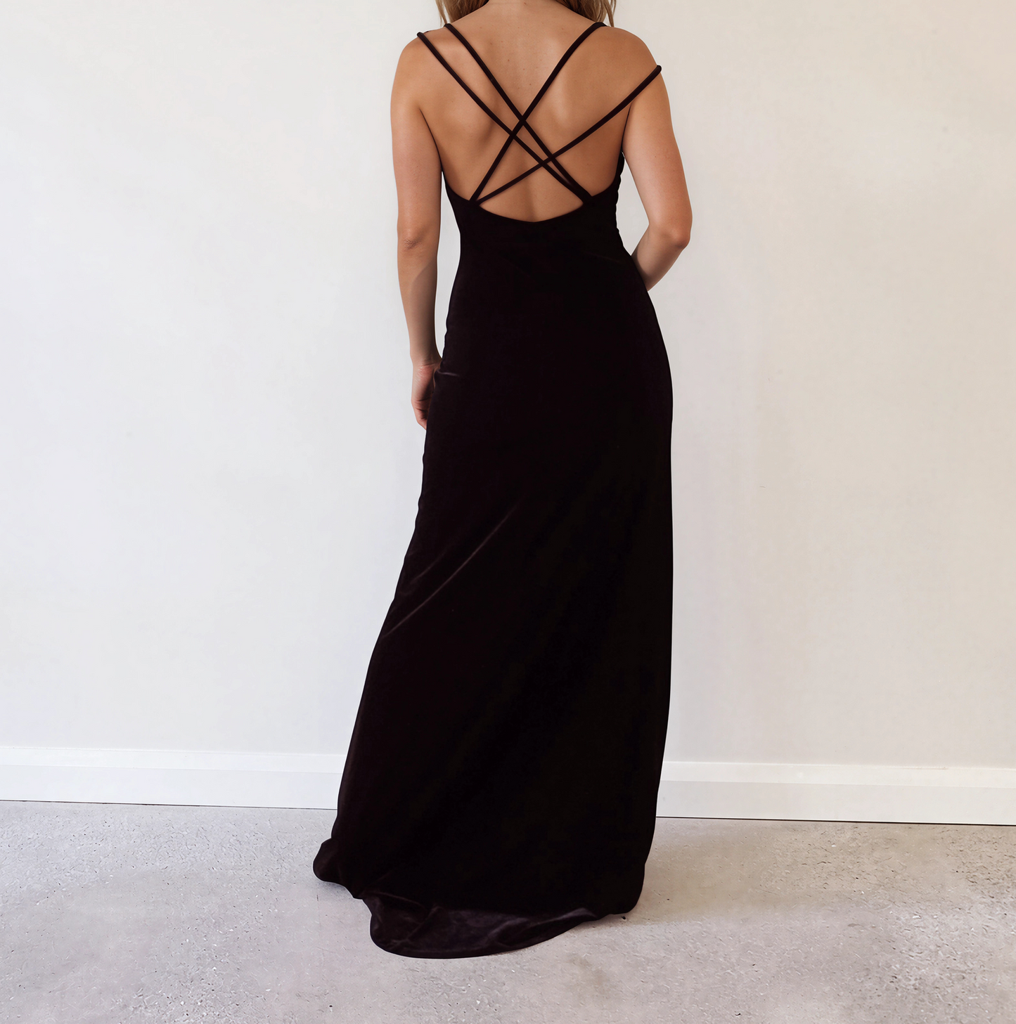 Back view of model wearing the black Saba velour floor-length maxi dress with spaghetti straps.