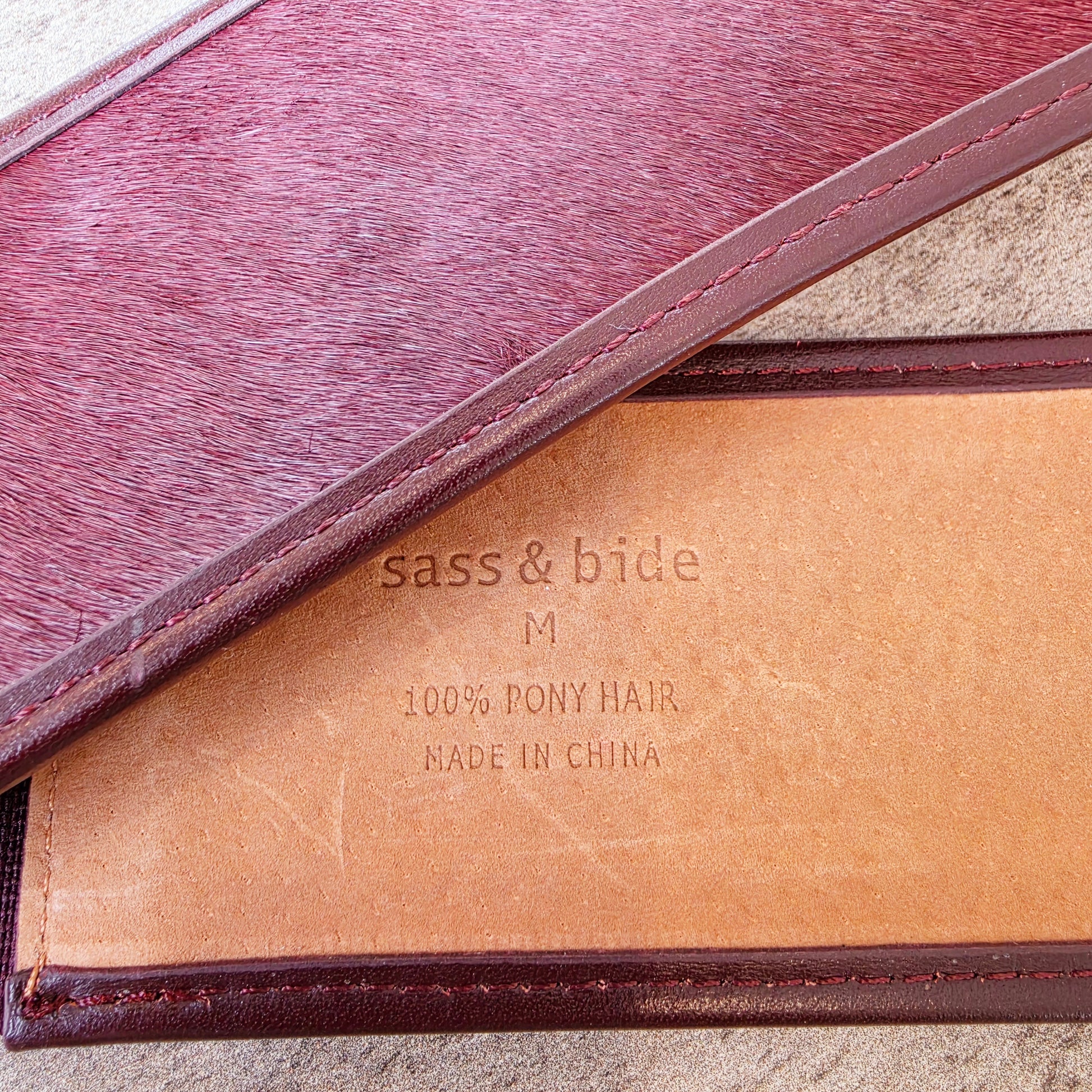 Close-up of the western style leather belt with 'sass & bide' branding and text showing 100% pony hair