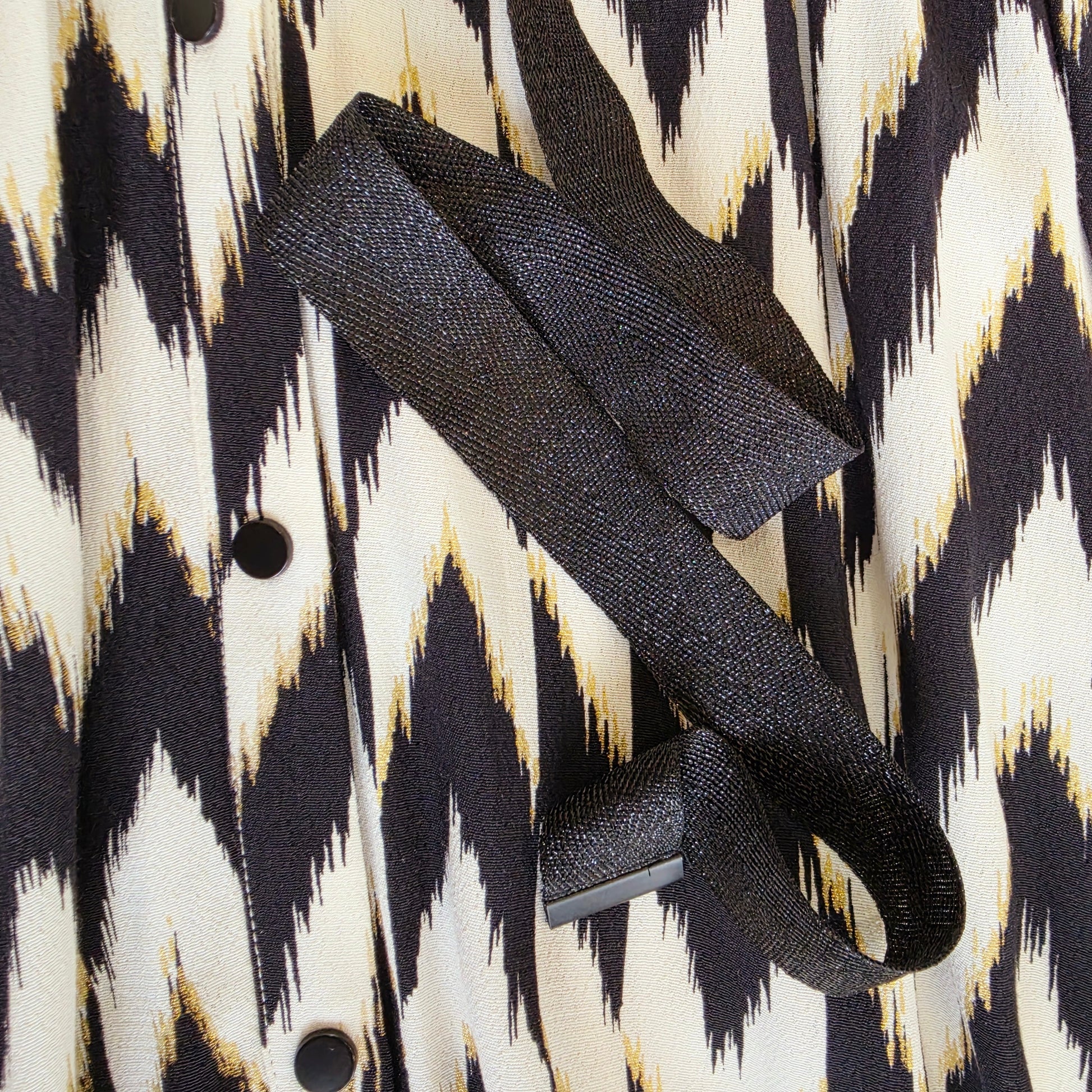 Close-up of the Sass & Bide Broken Chevron Dress waist tie in textured black woven fabric with metal-tipped ends.
