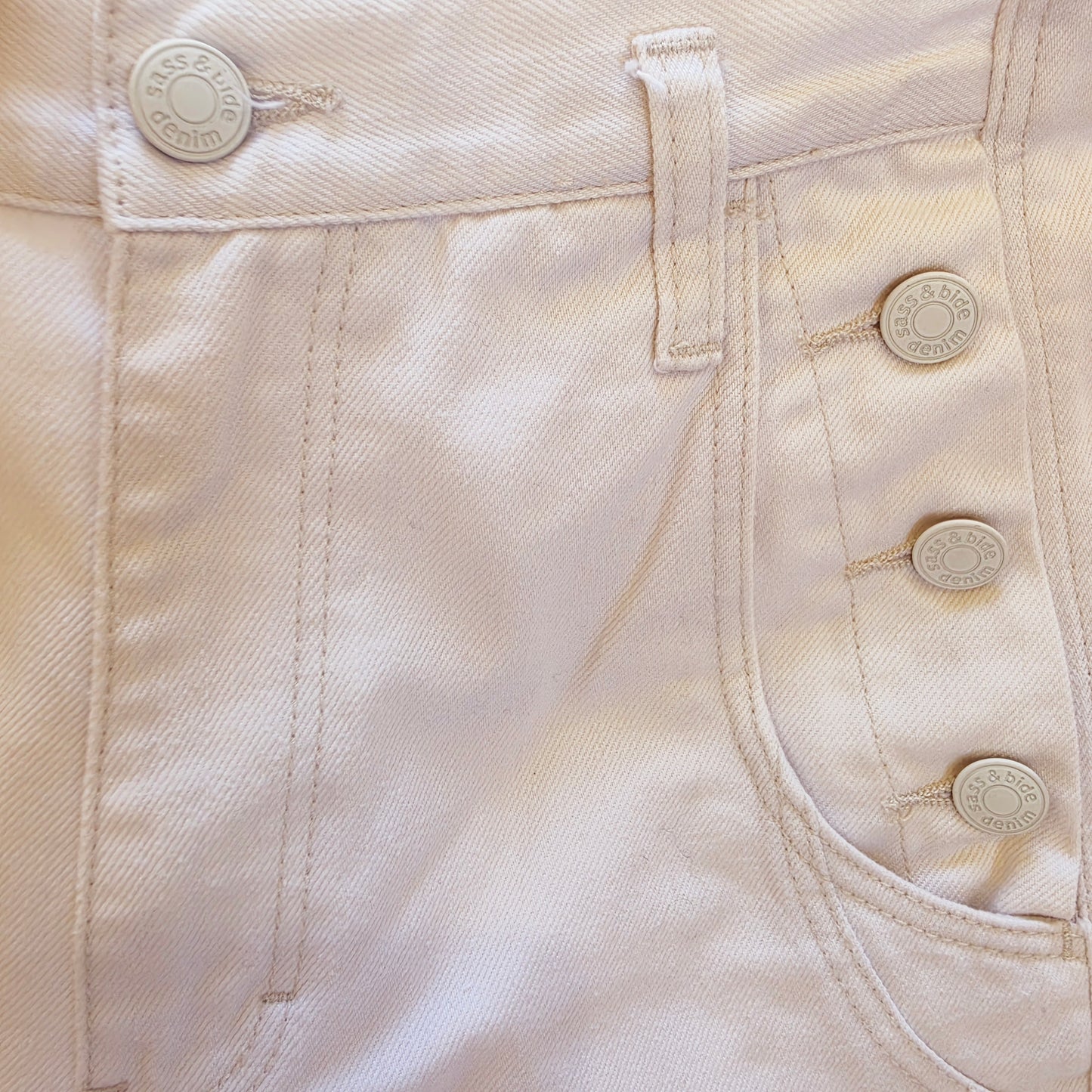 Close-up of the Sass & Bide My mind Jeans showing the waistband, belt loop, front pocket, and three decorative buttons on the side.
