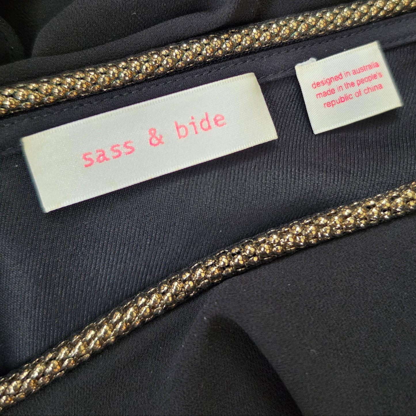 Close-up of the label inside the Sass & Bide showing the brand label and gold metallic braided trim.