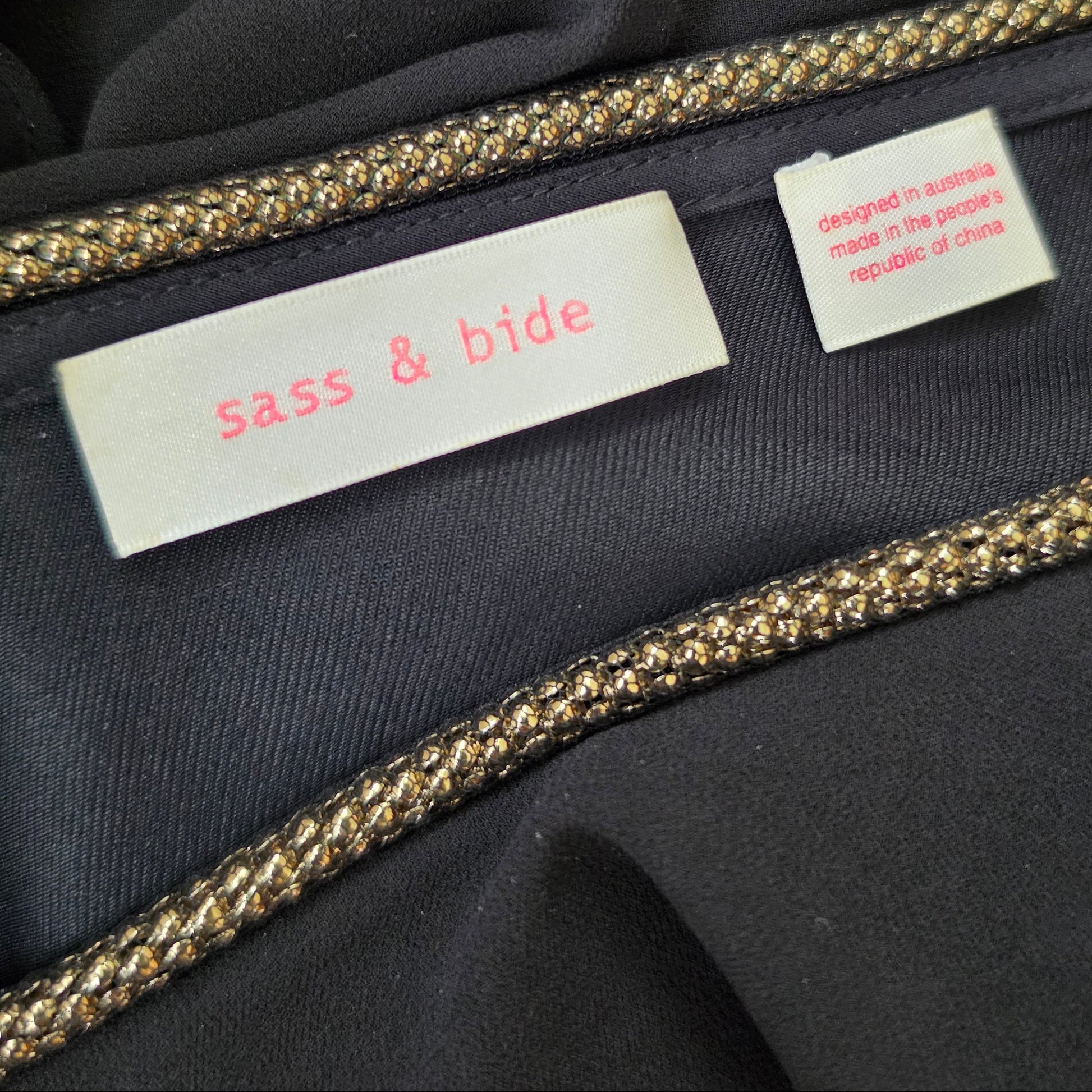 Close-up of the label inside the Sass & Bide showing the brand label and gold metallic braided trim.