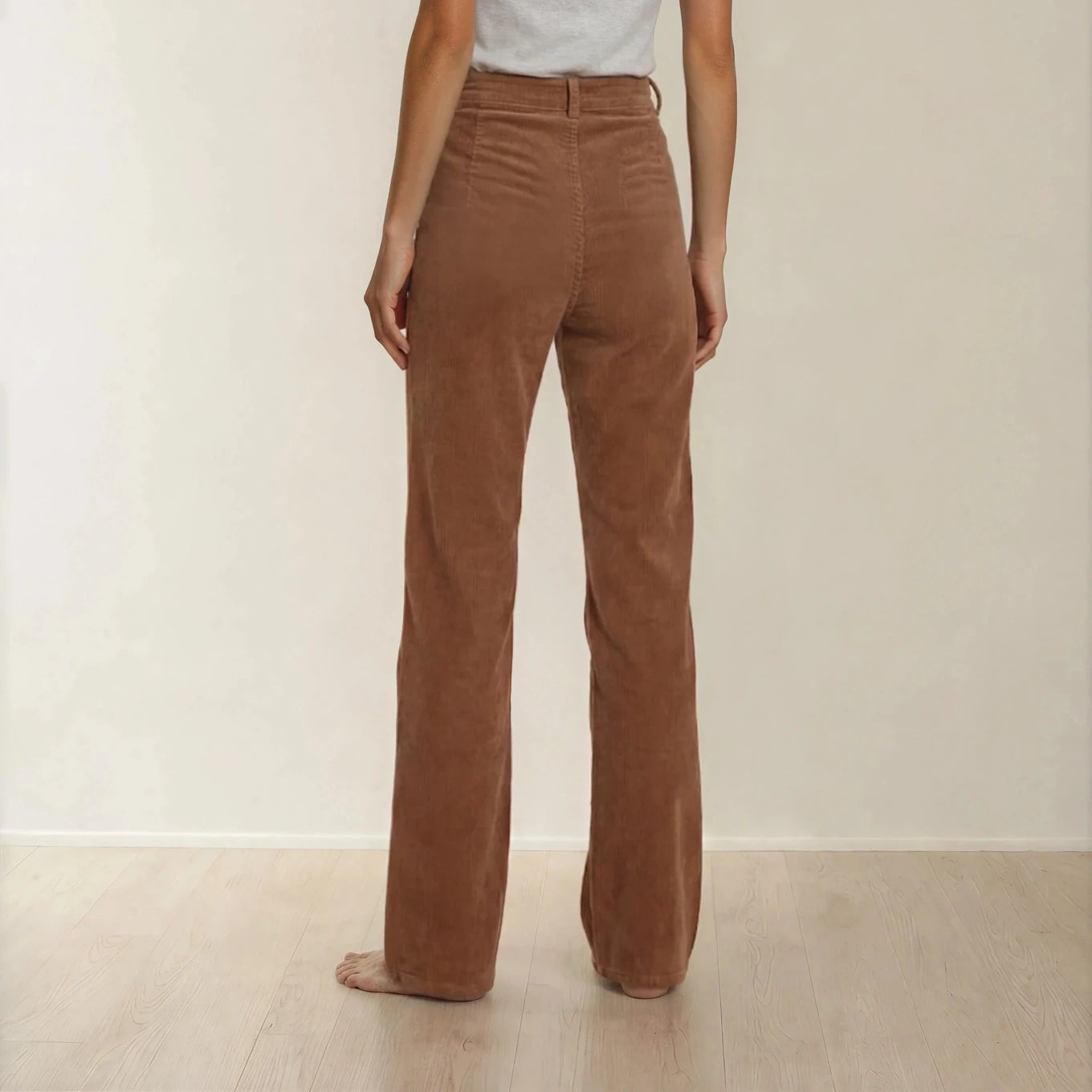 Back view of model wearing the rust coloured Scanlan Theodore corduroy pants, showing the refined cut, high waist and straight leg style. 