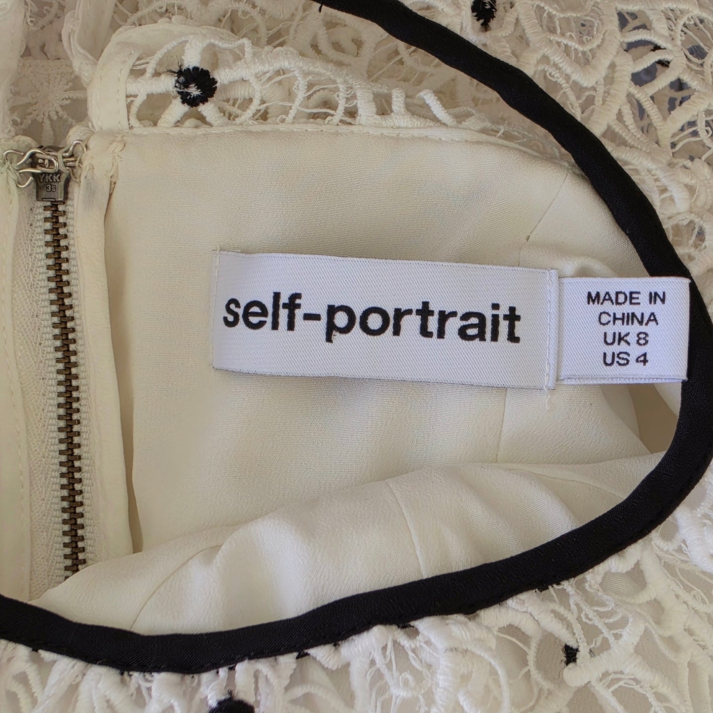 Close-up of a garment with 'self-portrait' label on a lace background