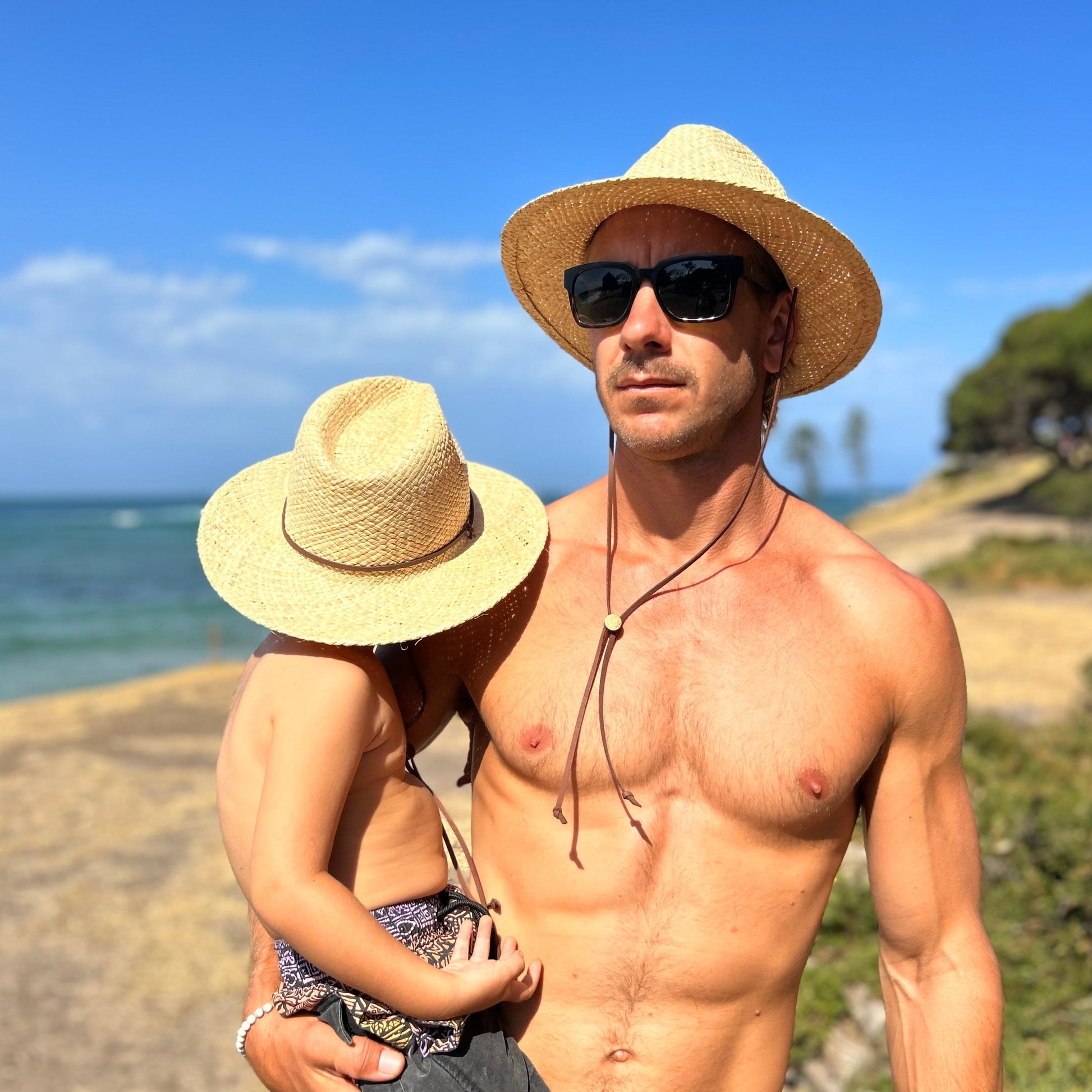 Man and child wearing Shayd straw hats with removable straps