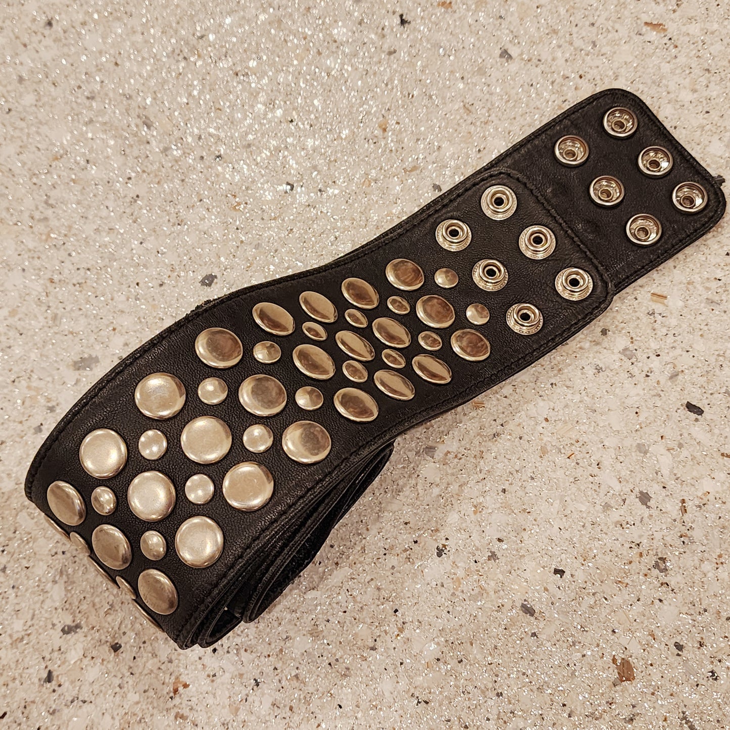 Closer view of the Sirocco leather belt showing the light surface scuffing, snap closure and studded details.
