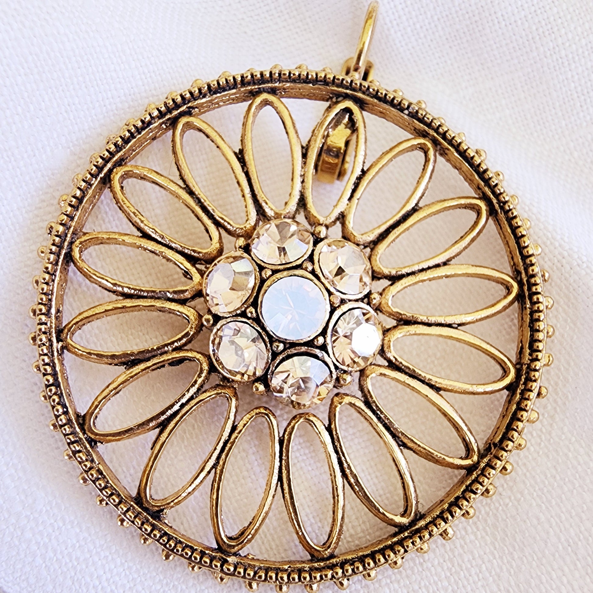 Close-up of the Sunflare earrings showing the crystal centre and textured gold petal loops.