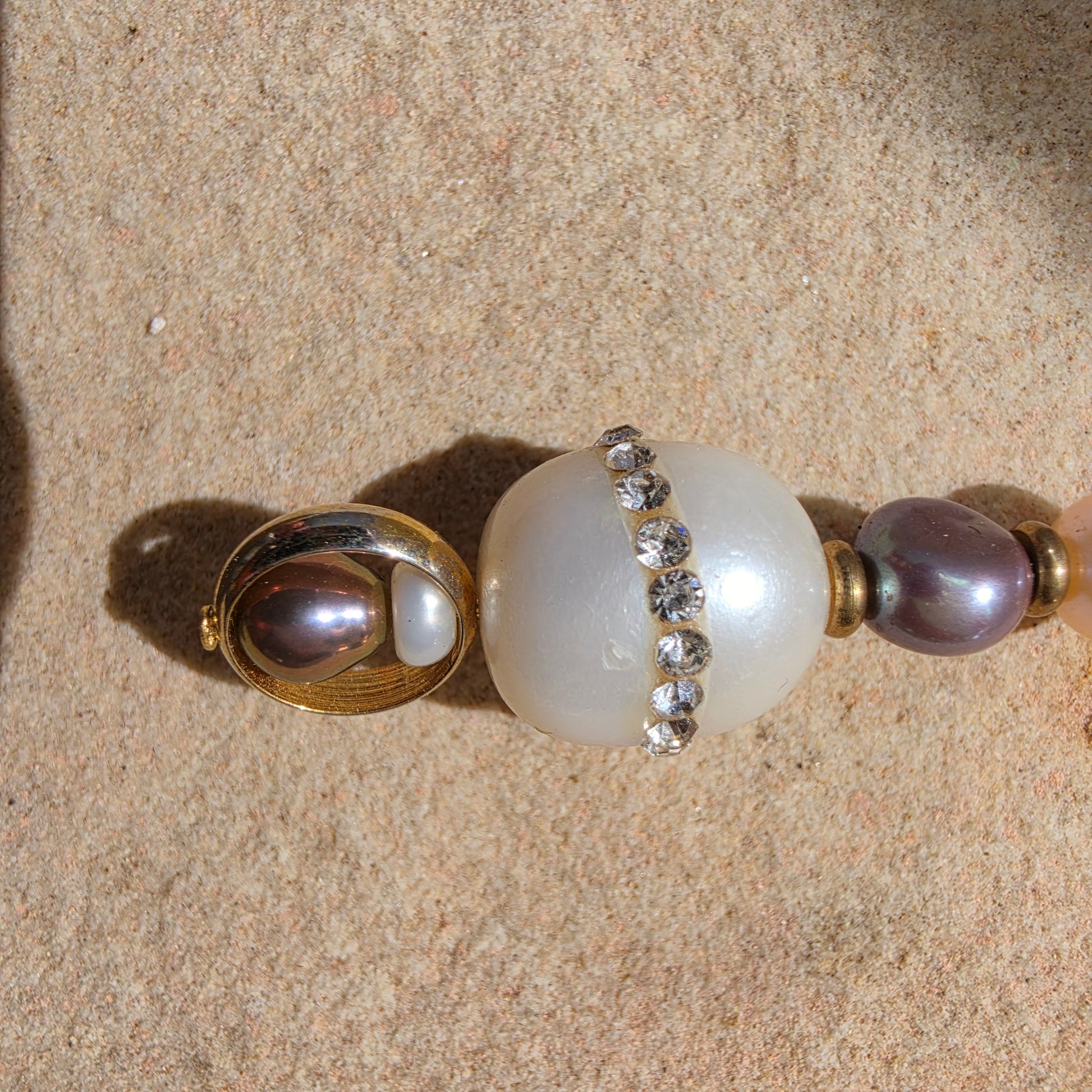 Close up of the Versamel earrings showing the wonky diamantes and fading of gold plating on small loop and chipping on the pearl.