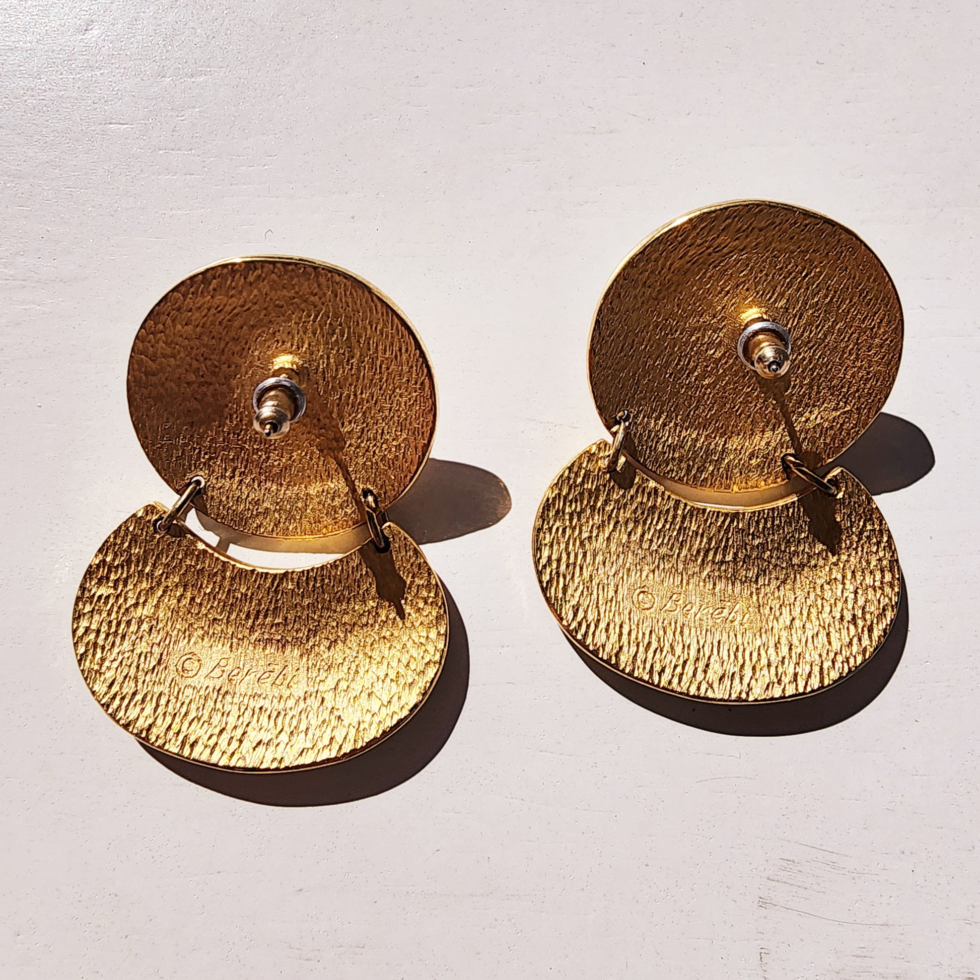 Back view of vintage Berebi gold-tone earrings with stud fastening and brand name engraving.