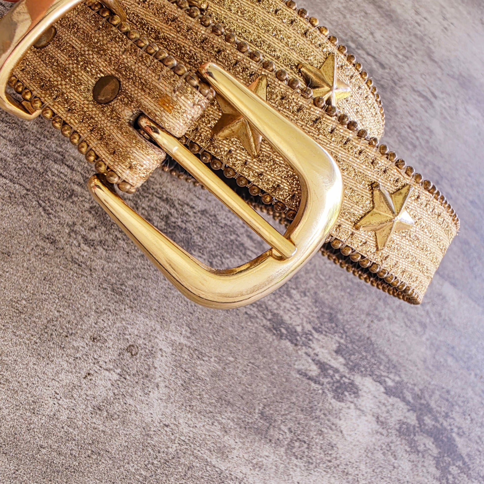 Close up of gold buckle and star stud detail on vintage Elite metallic belt
