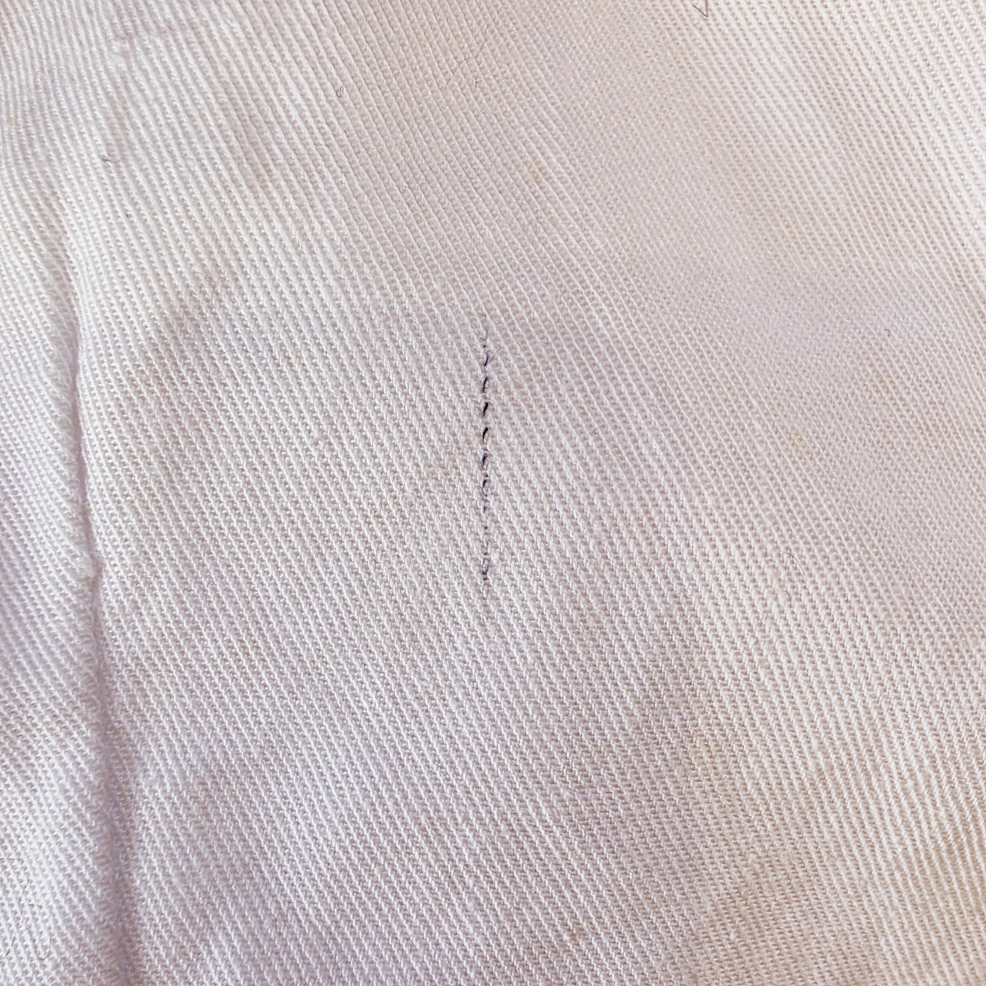Close-up of small random discoloured thread on vintage Katies white cropped pants.