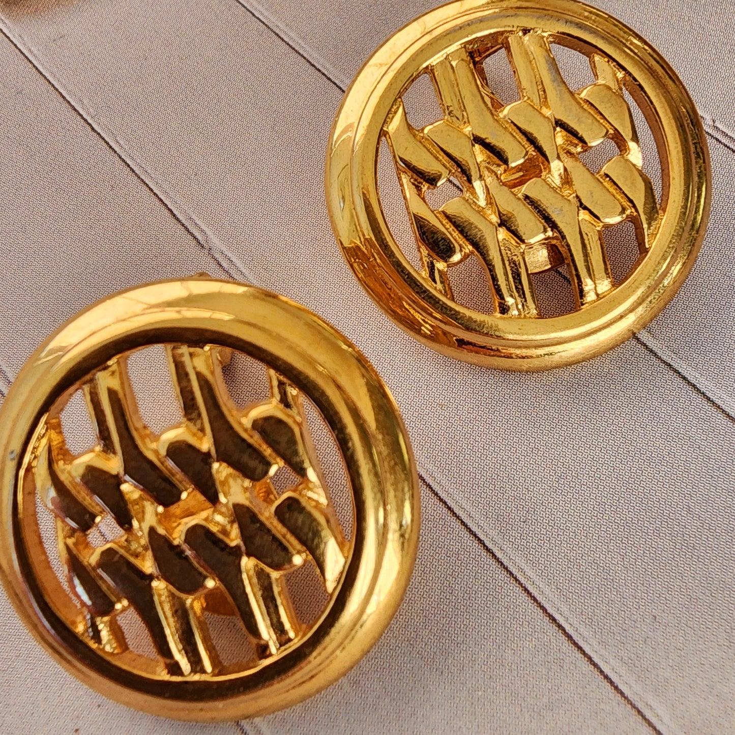 Close-up view of the Vintage Monet, gold-toned earring, showing the classic woven pattern and slight surface scratches.