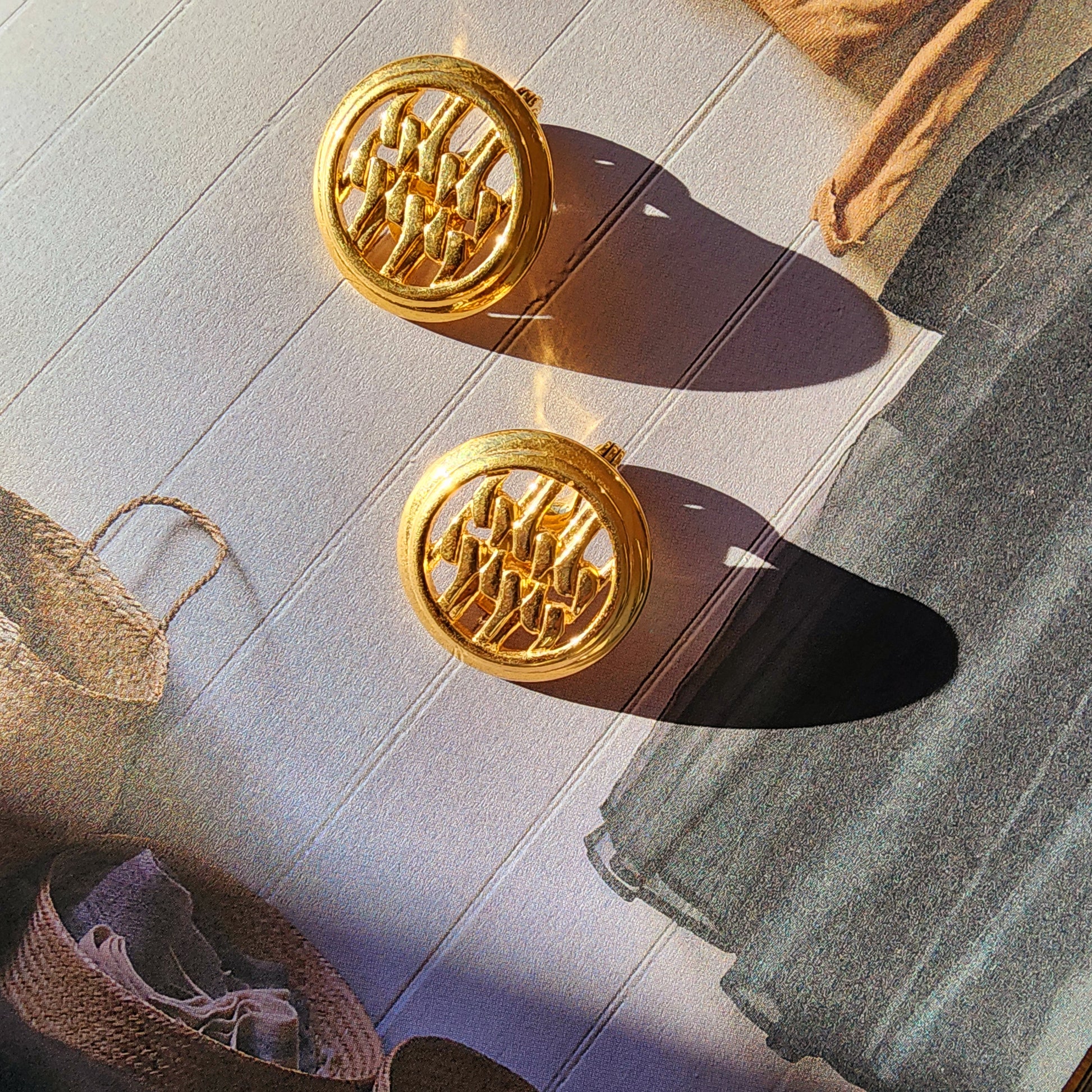 Image showing the Vintage Monet gold-toned round clip-on earrings. Photo taken in bright light to show the light surface scuffs. 