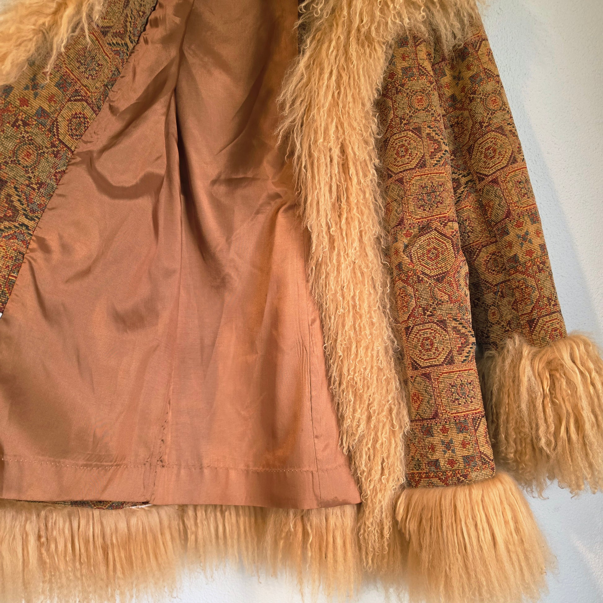 A close-up of the vintage Pennyy Lane bohemian patterned jacket with long beige Mongolian lamb trim along the collar, cuffs, and hem.