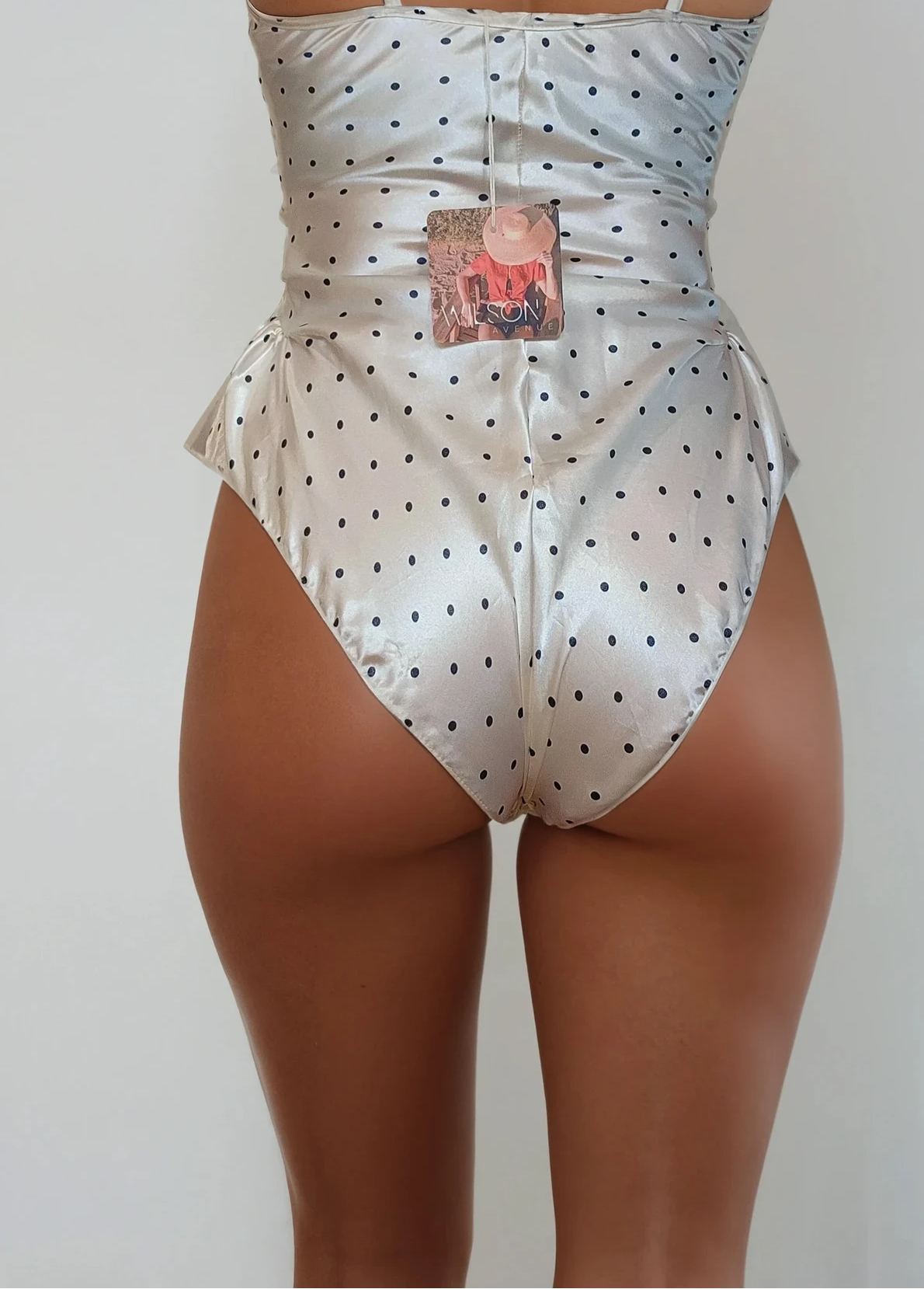 Model showing back of vintage one piece lingerie, showing the little frills at the hips.