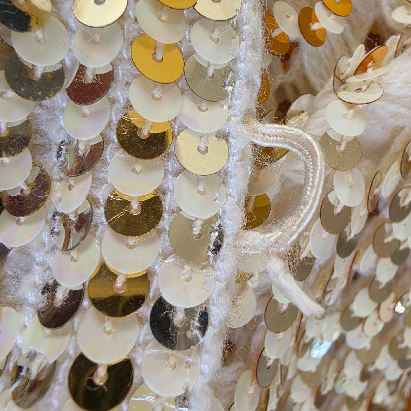close up view of  one of the button loops of the vintage sequin dinner jacket, showing the fraying fabric from age and wear