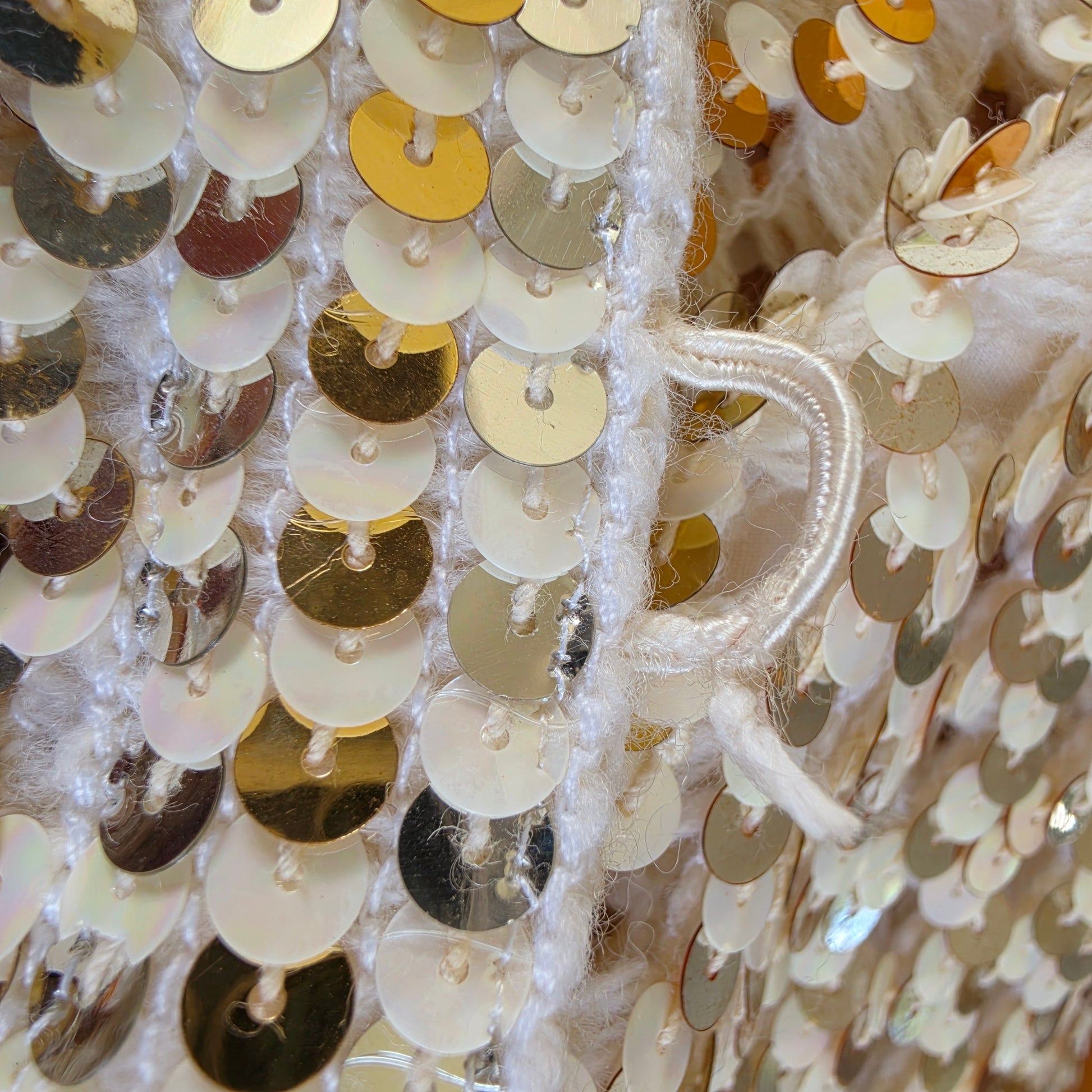 close up view of  one of the button loops of the vintage sequin dinner jacket, showing the fraying fabric from age and wear