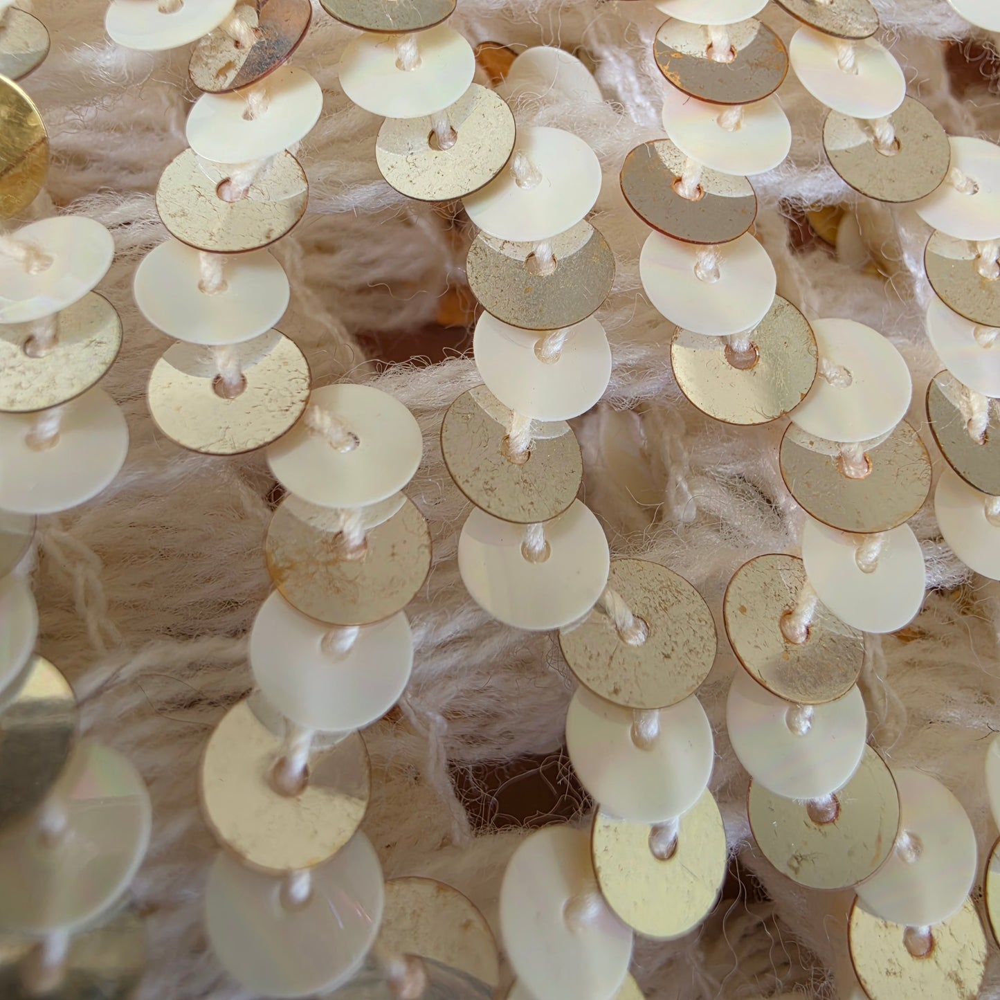 Close-up of gold and white circular sequins with some fading from age on the vintage sequin dinner jacket