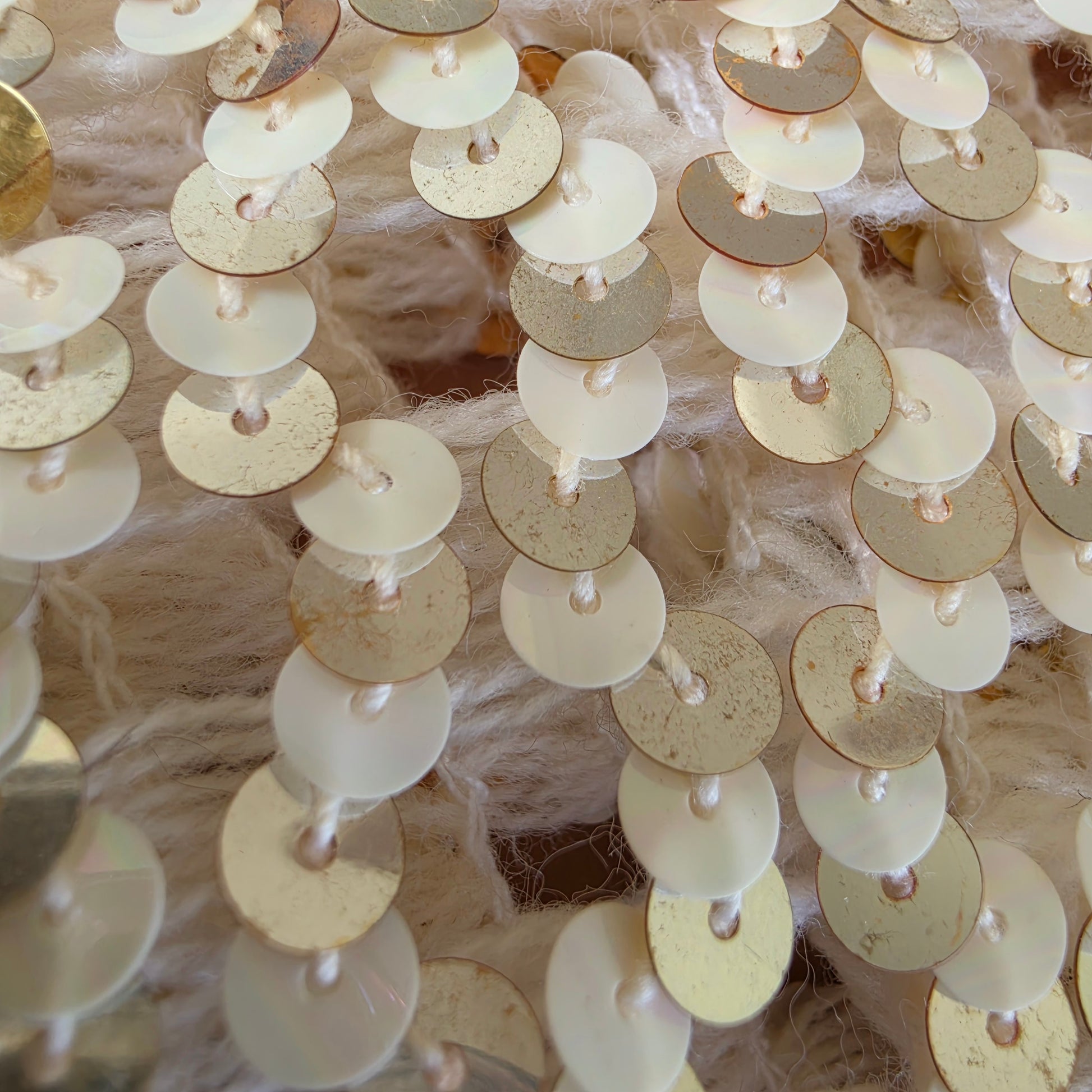 Close-up of gold and white circular sequins with some fading from age on the vintage sequin dinner jacket