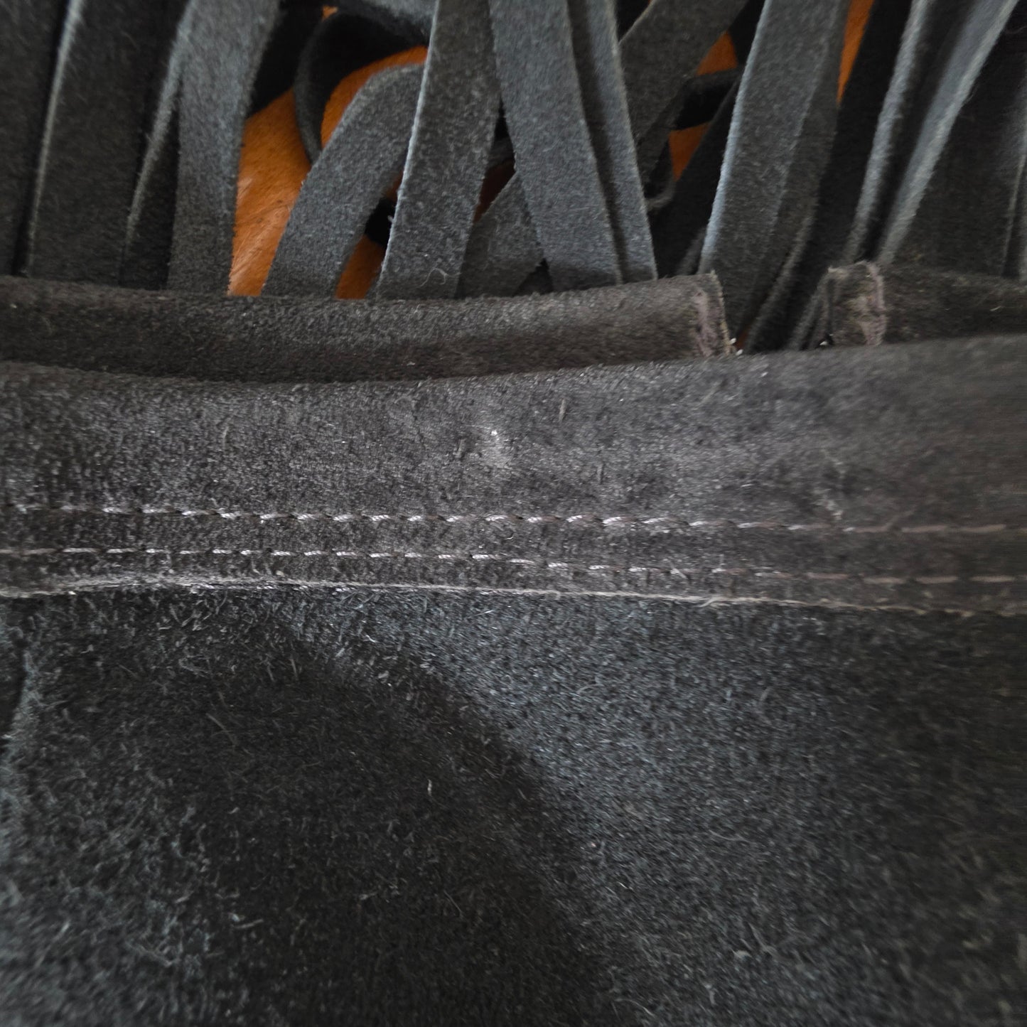 Close up view of the waist band on the vintage suede fringe skirt, showing signs of wear.