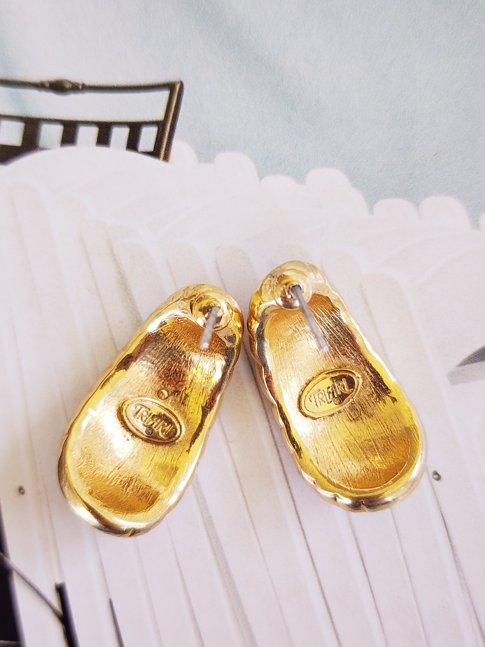 A close up of the back of vintage Trifari earrings, showing the logo and copyright symbol.