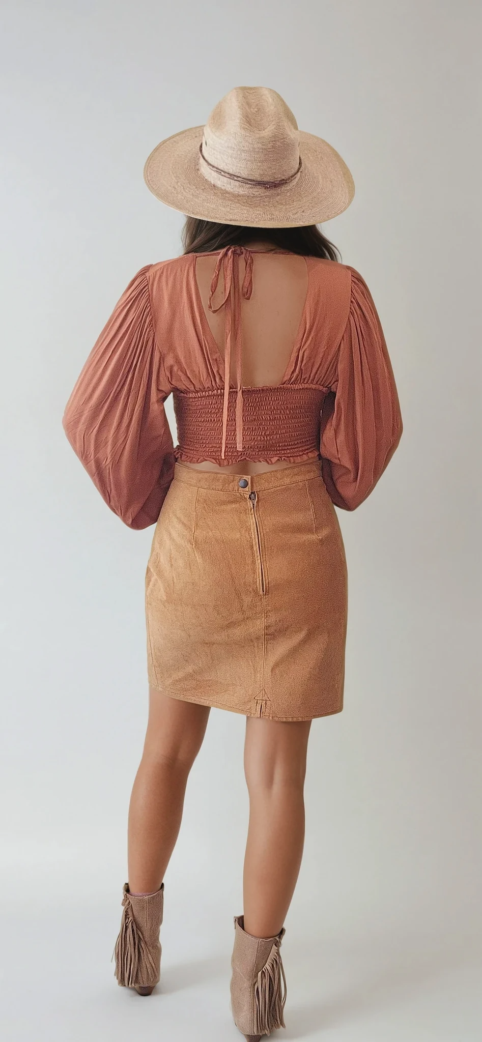 Back view of Vintage Vinetti suede skirt in tan mustard. Showing the zip and button closure and small back split. Styled on a model with fringe boots and a western hat.