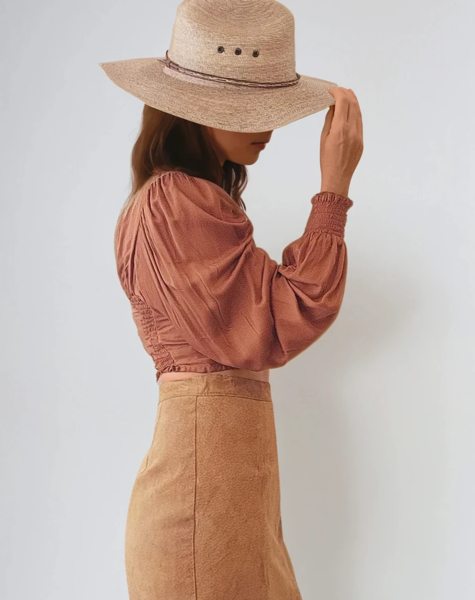 Close-up view of the Vintage Vinetti tan suede skirt, showing the waistband and side seam. Styled with  a bohemian-style Remi Lane blouse and a western hat.