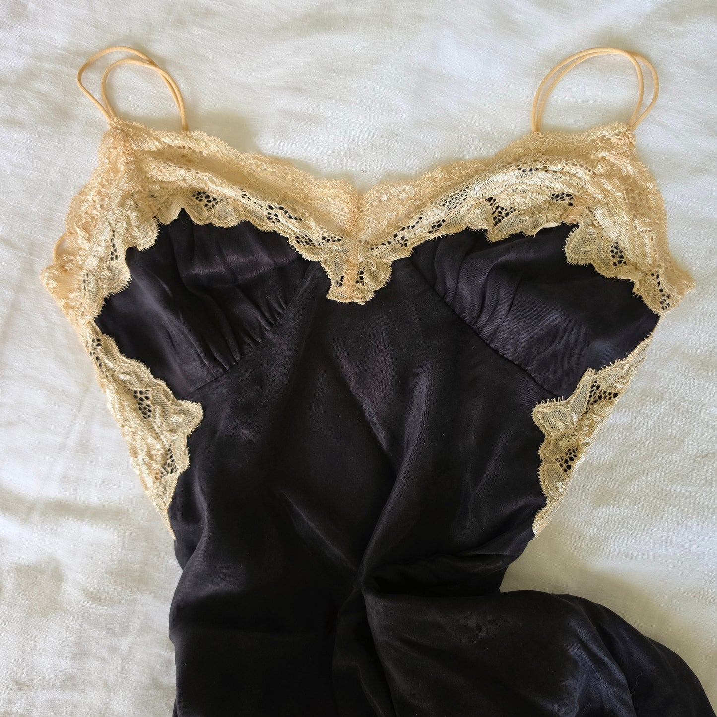 Flat lay image showing the lace panels and black slip dress with spaghetti straps.