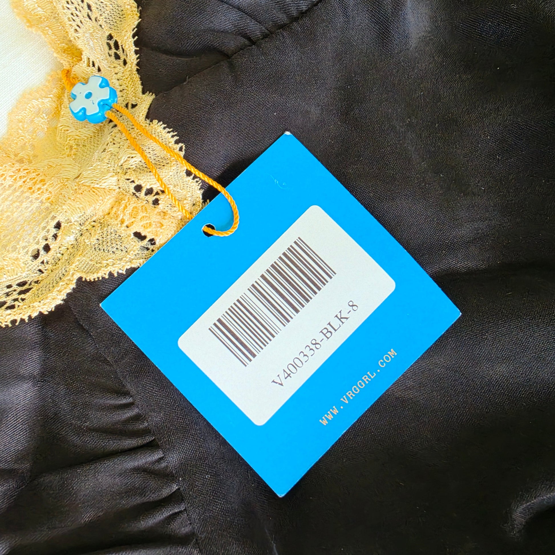 Photo showing the swing tag with the item number V400338-BLK-8 on the Verge Girl lace mini slip dress