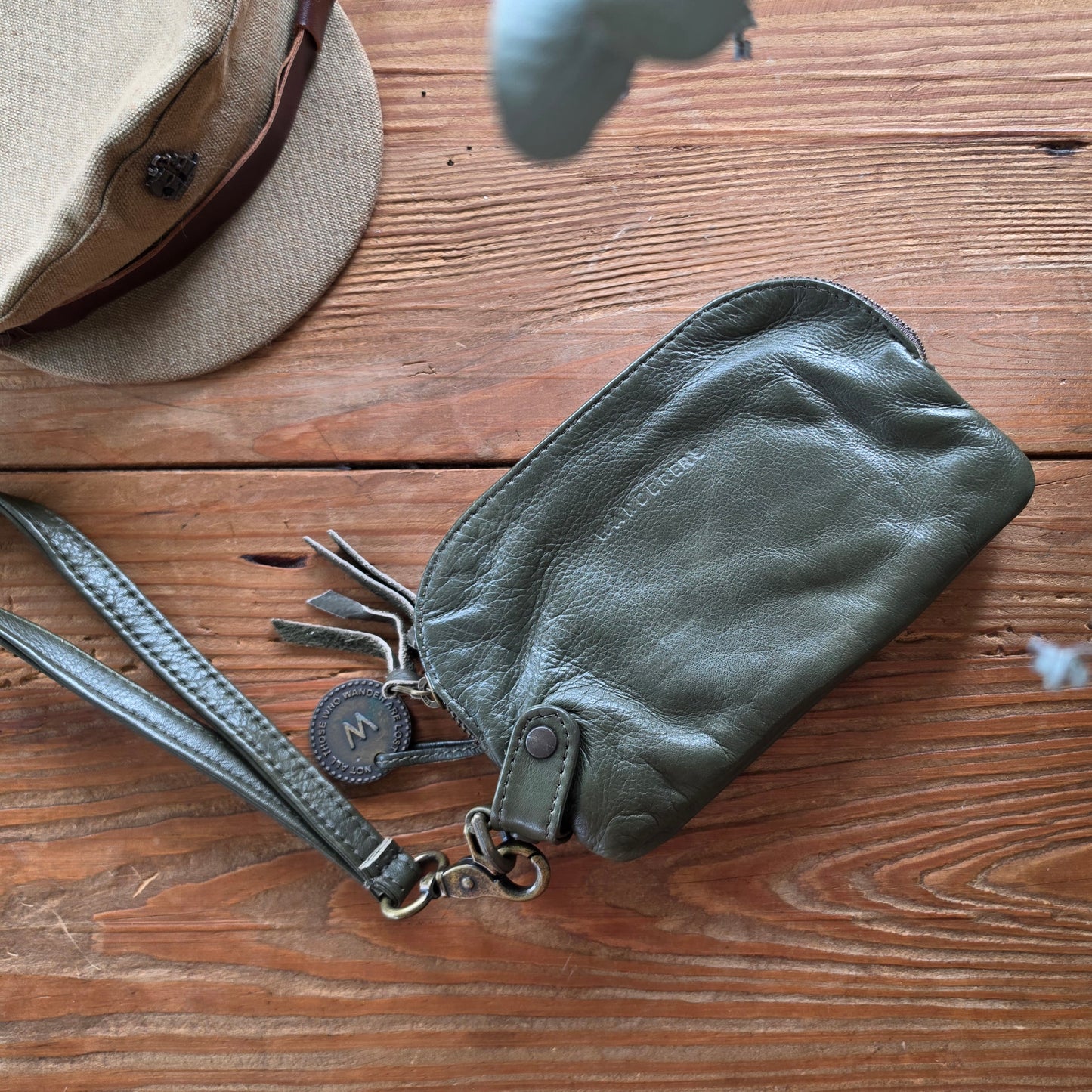 Back view of The Wanderers Venetian wallet in olive leather with wrist strap styled on timber