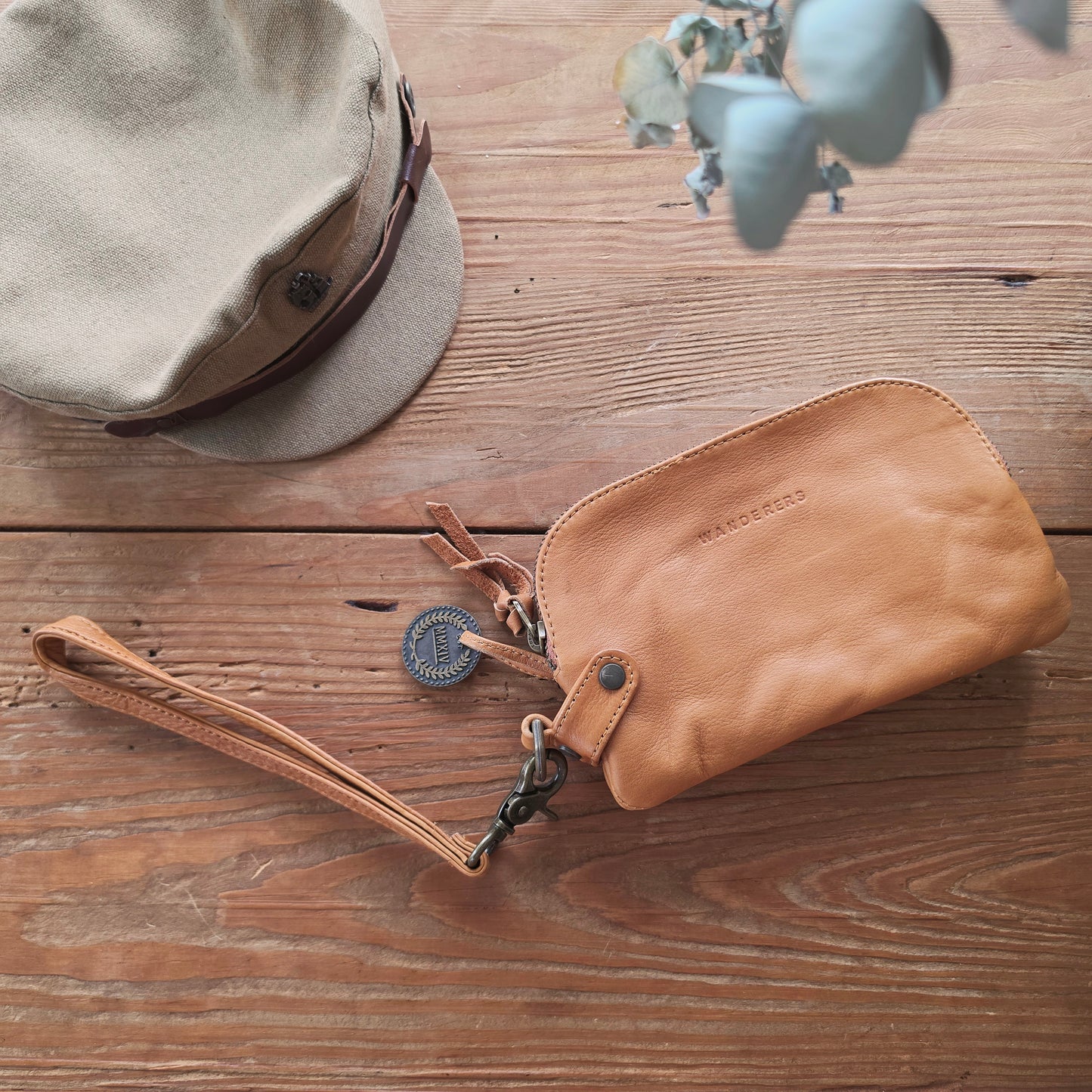 Back view of The Wanderers Venetian wallet in tan leather with wrist strap on timber surface