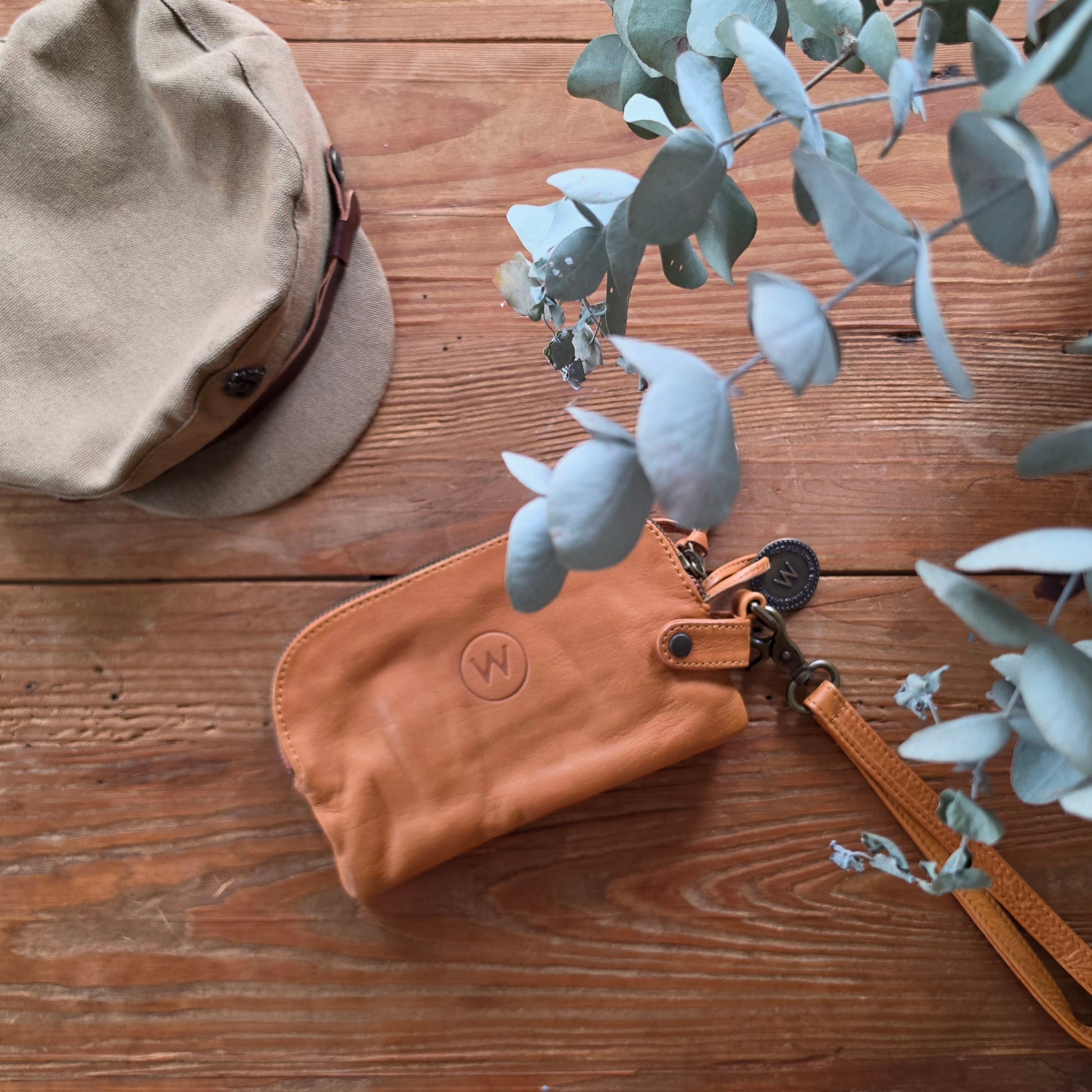 The Wanderers Venetian wallet in tan leather with wrist strap on timber surface